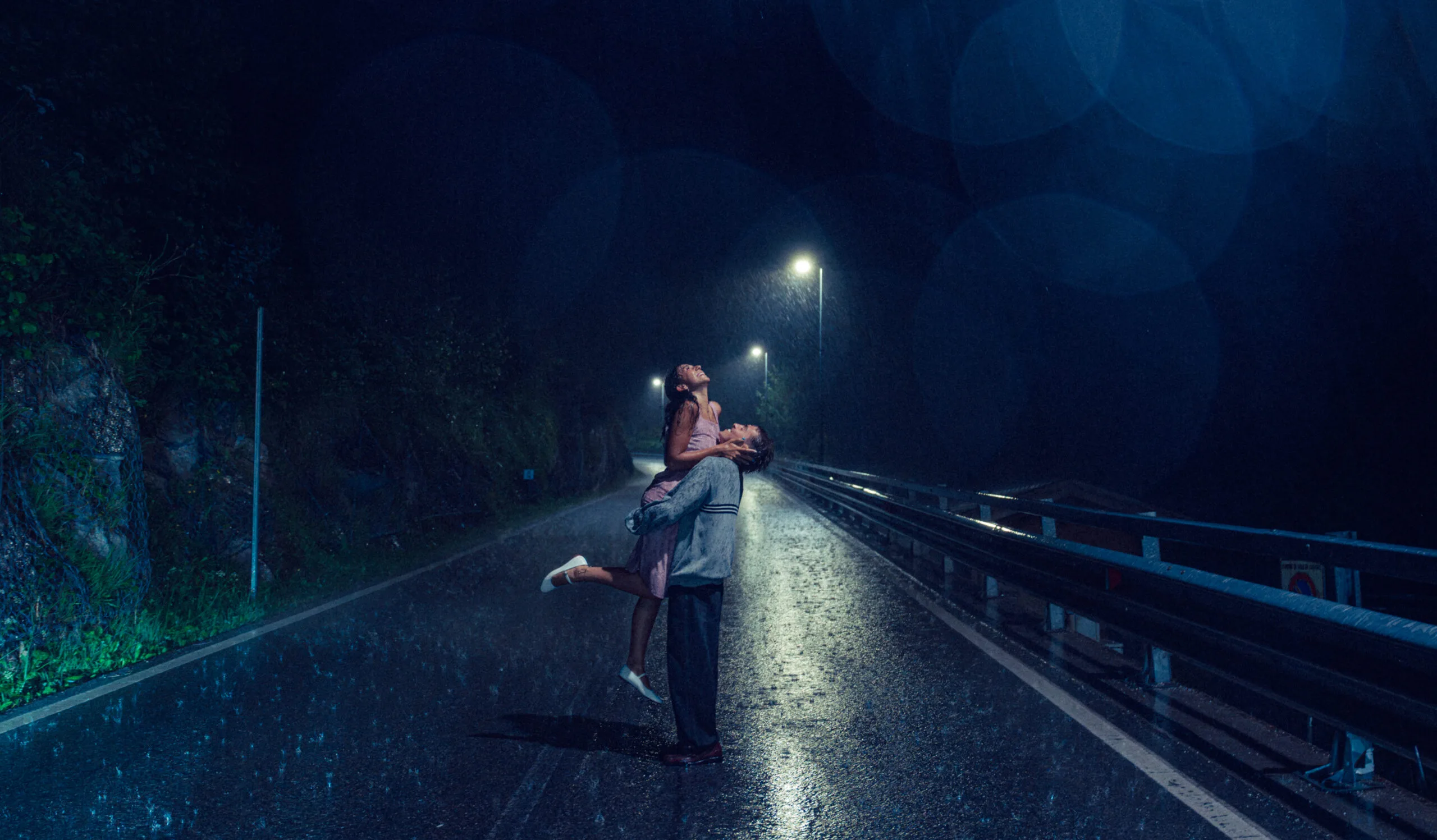 A cinematic photo of a couple dancing in the rain during night near the Dolomites.