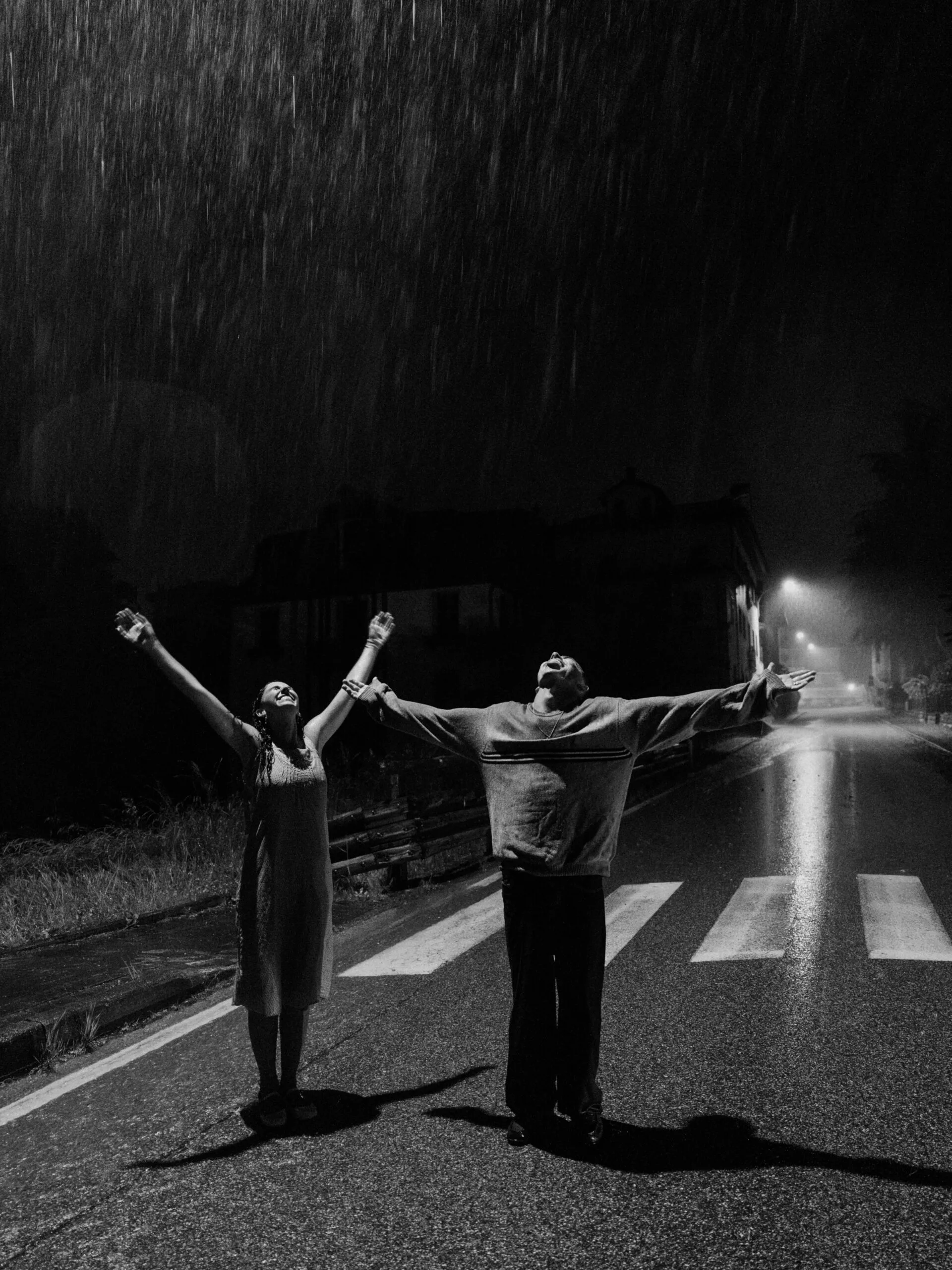 A cinematic photo of a couple dancing in the rain during night near the Dolomites.