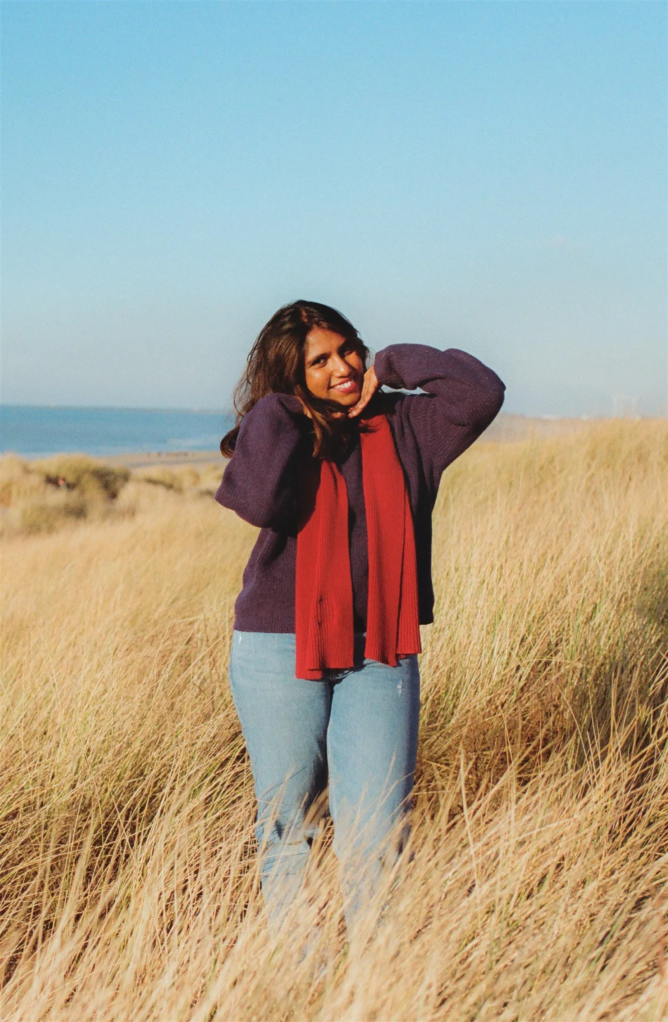 Kiki from Grainy Soul Photos posing in front of a beach in the Netherlands.