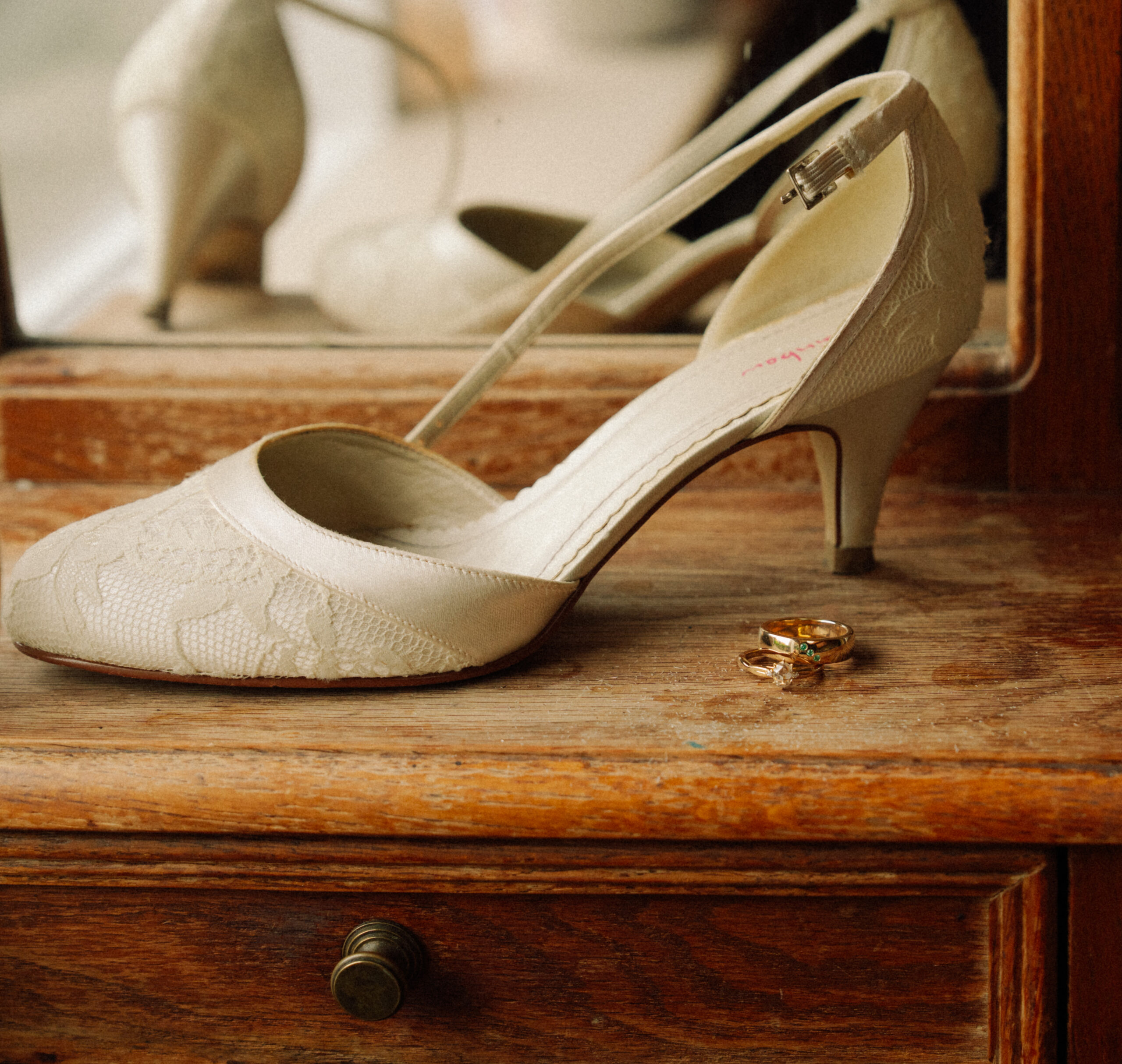 A wedding flat lay of shoes and rings taken inside a home.