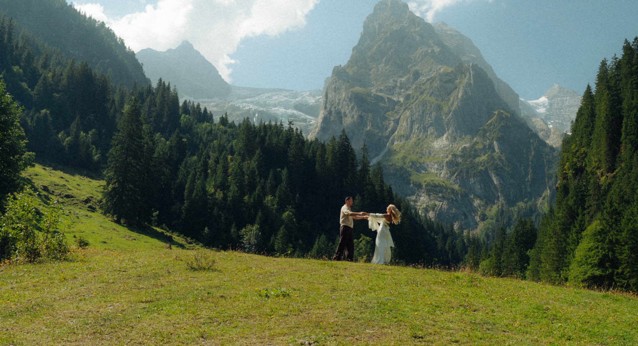 A cinematic photo of a couple posing in a meadow in Switzerland.