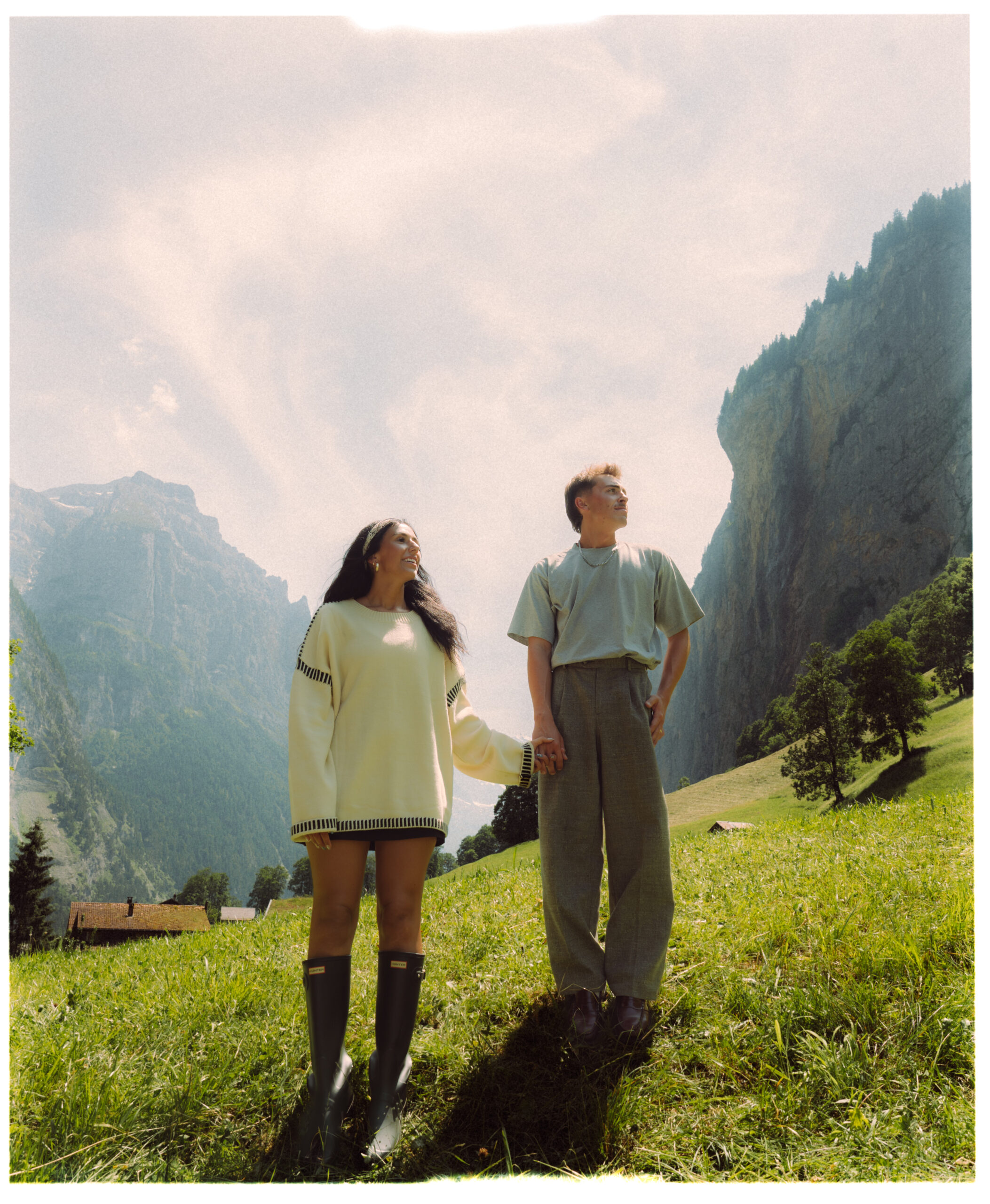A cinematic photo of a couple posing in a meadow in Lauterbrunnen.