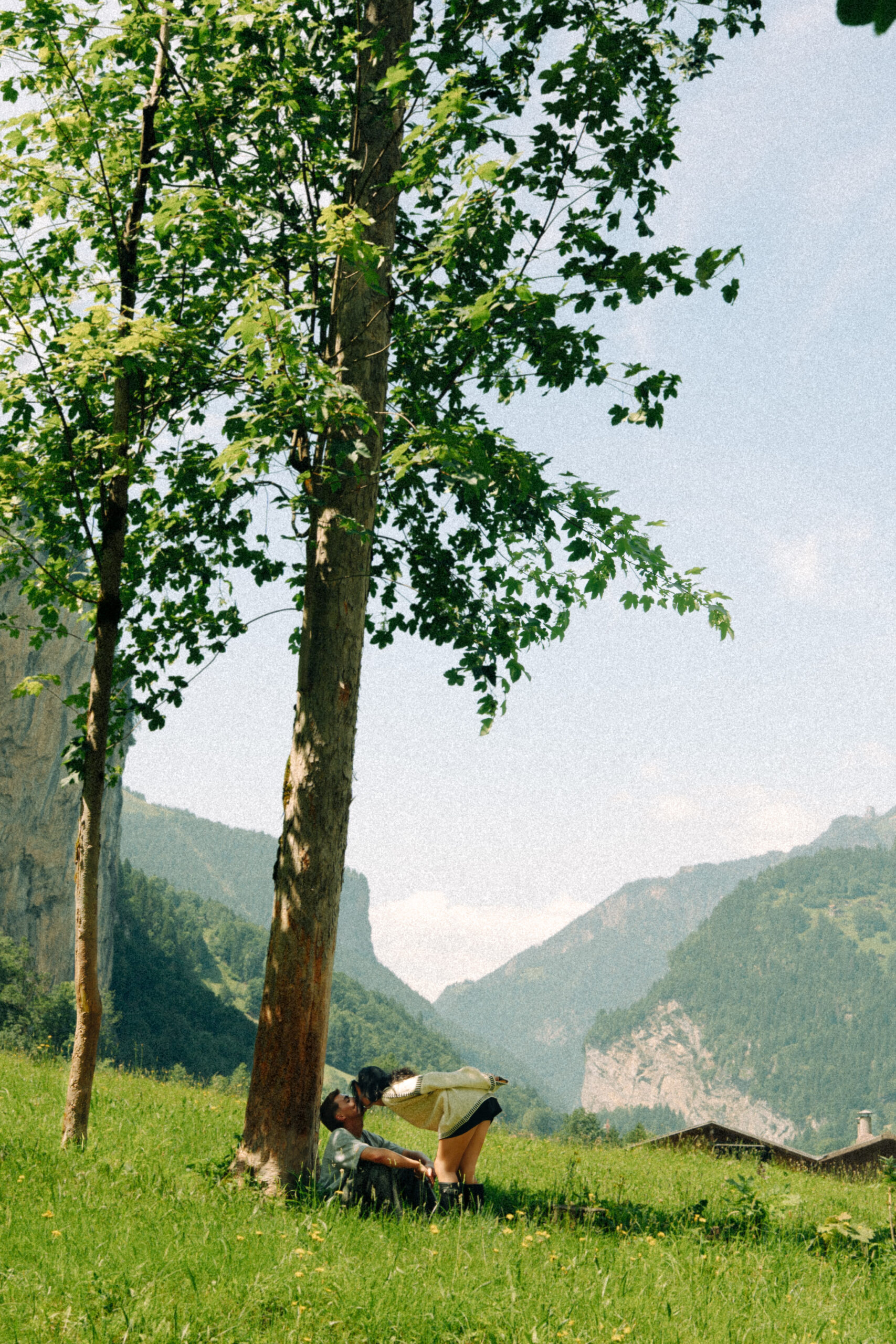 A cinematic photo of a couple posing in a meadow in Lauterbrunnen.
