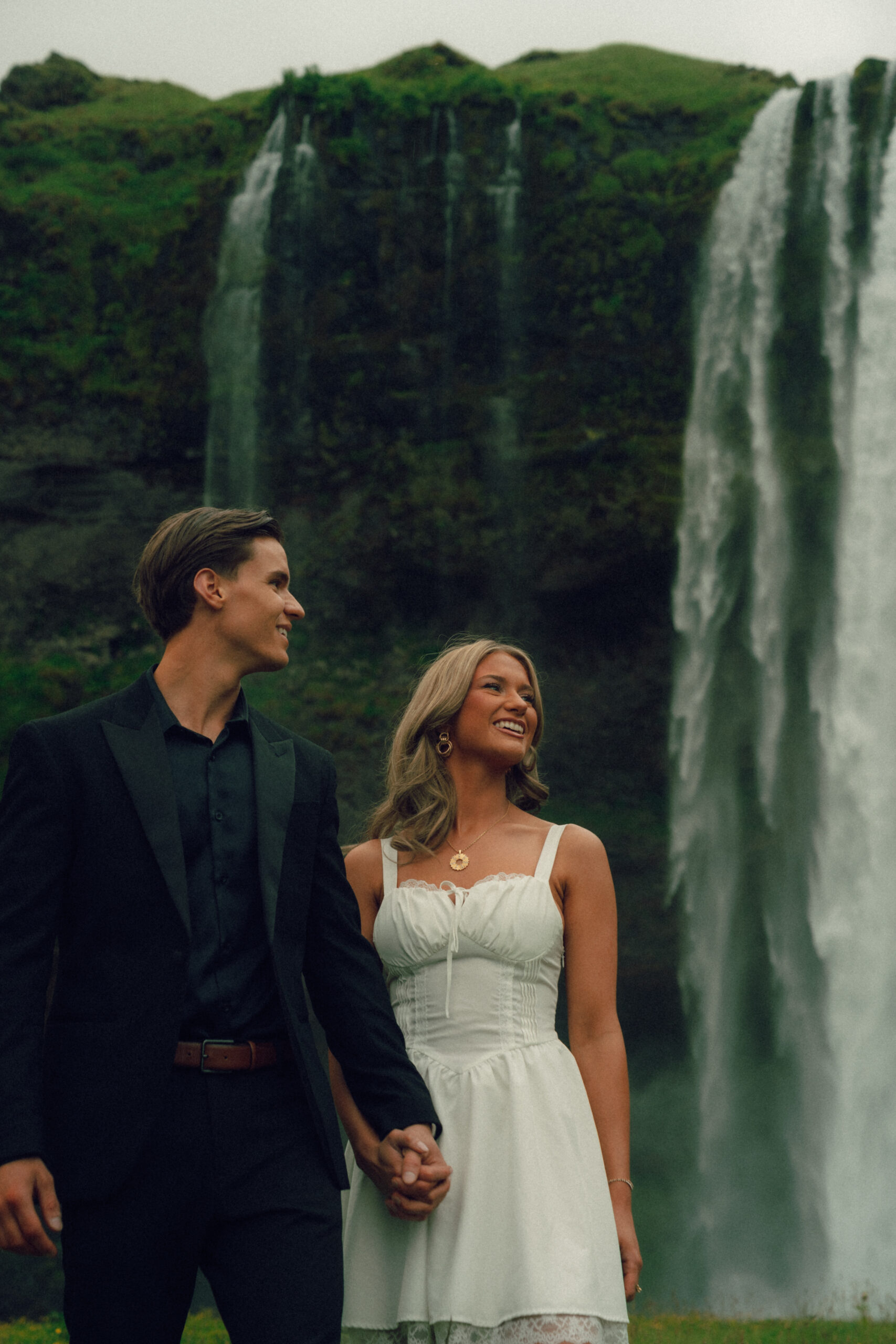A cinematic photo of a couple in front of a waterfall during their elopement in Iceland.