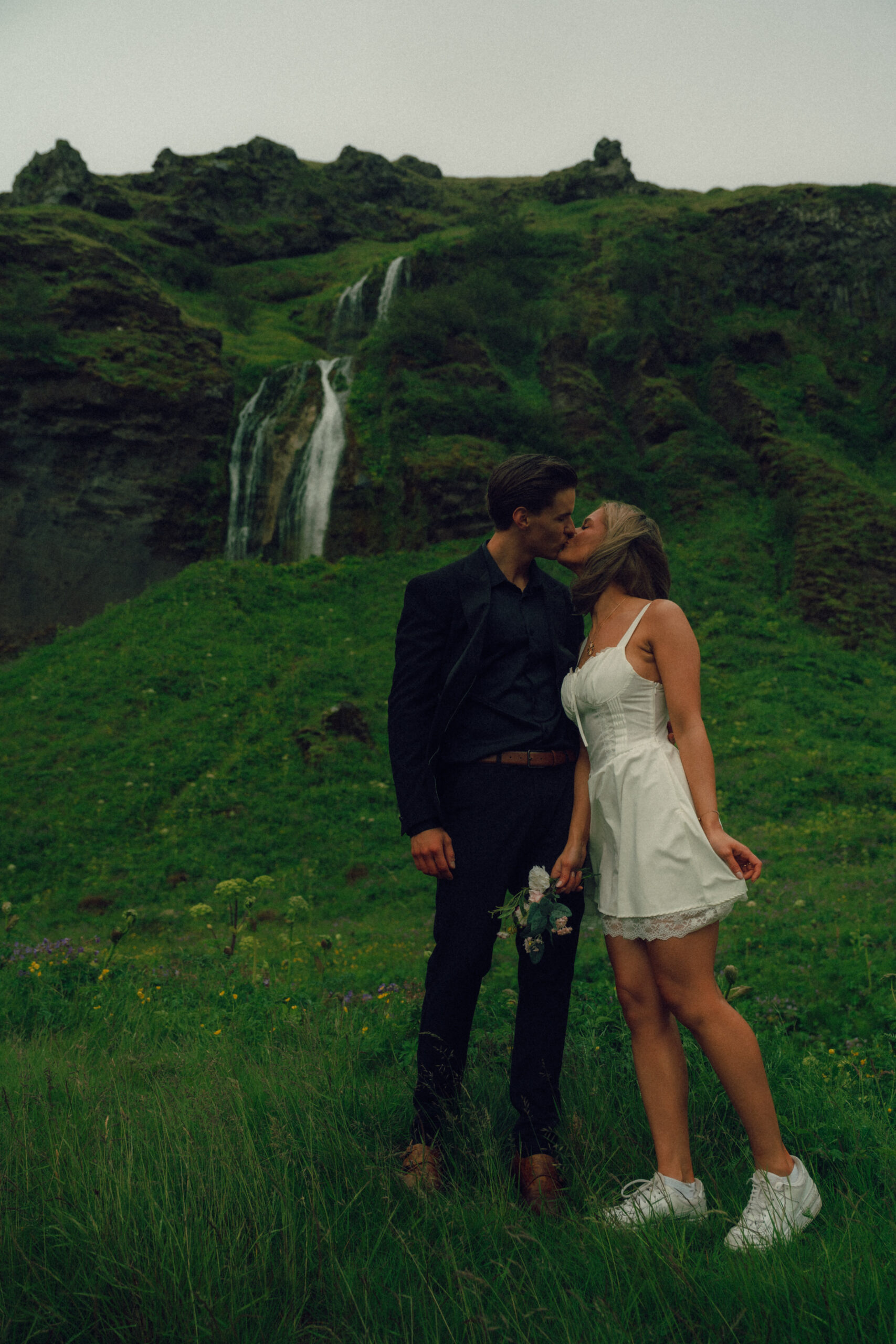 A cinematic photo of a couple in front of a waterfall during their elopement in Iceland.