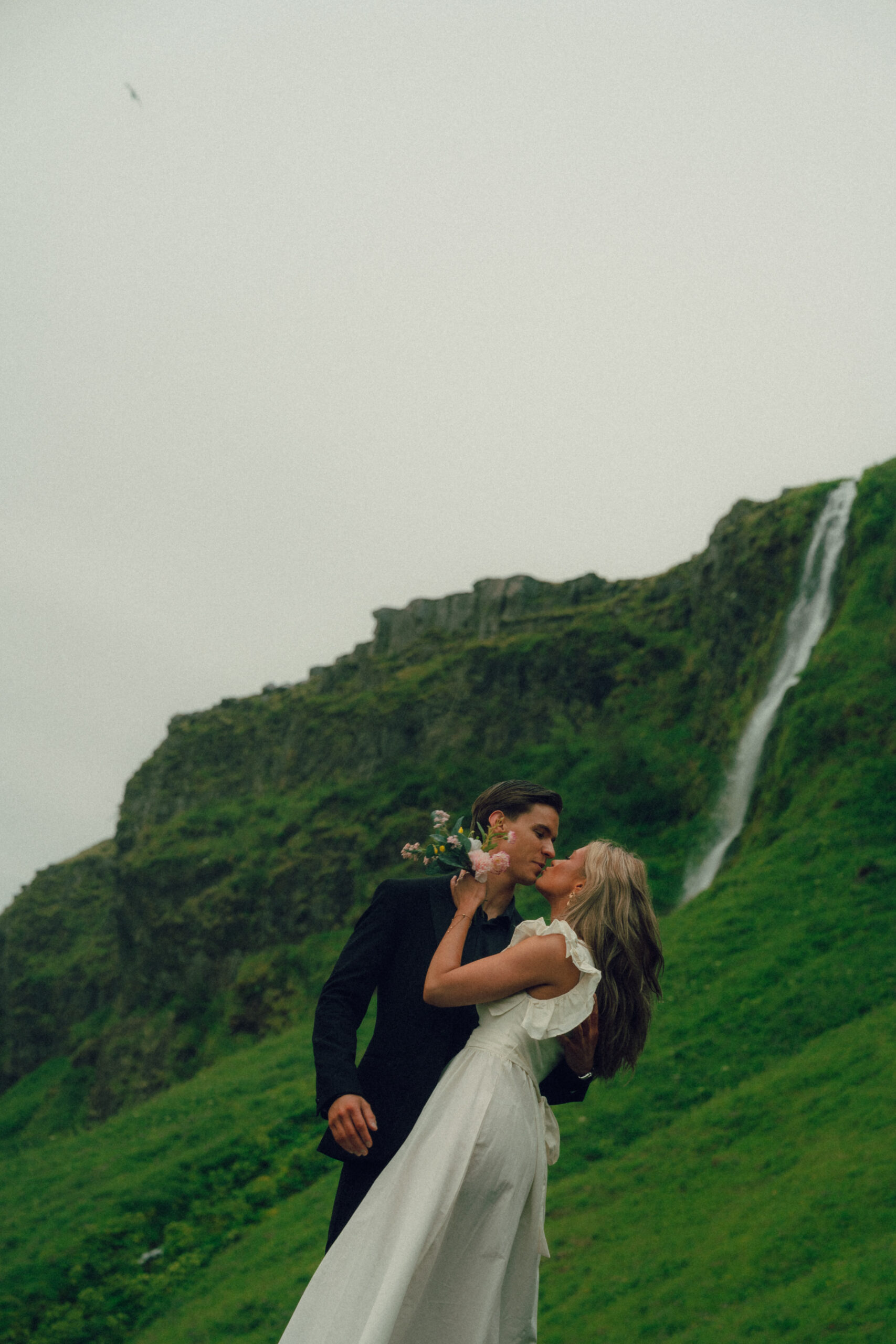 A cinematic photo of a couple in front of a waterfall during their elopement in Iceland.