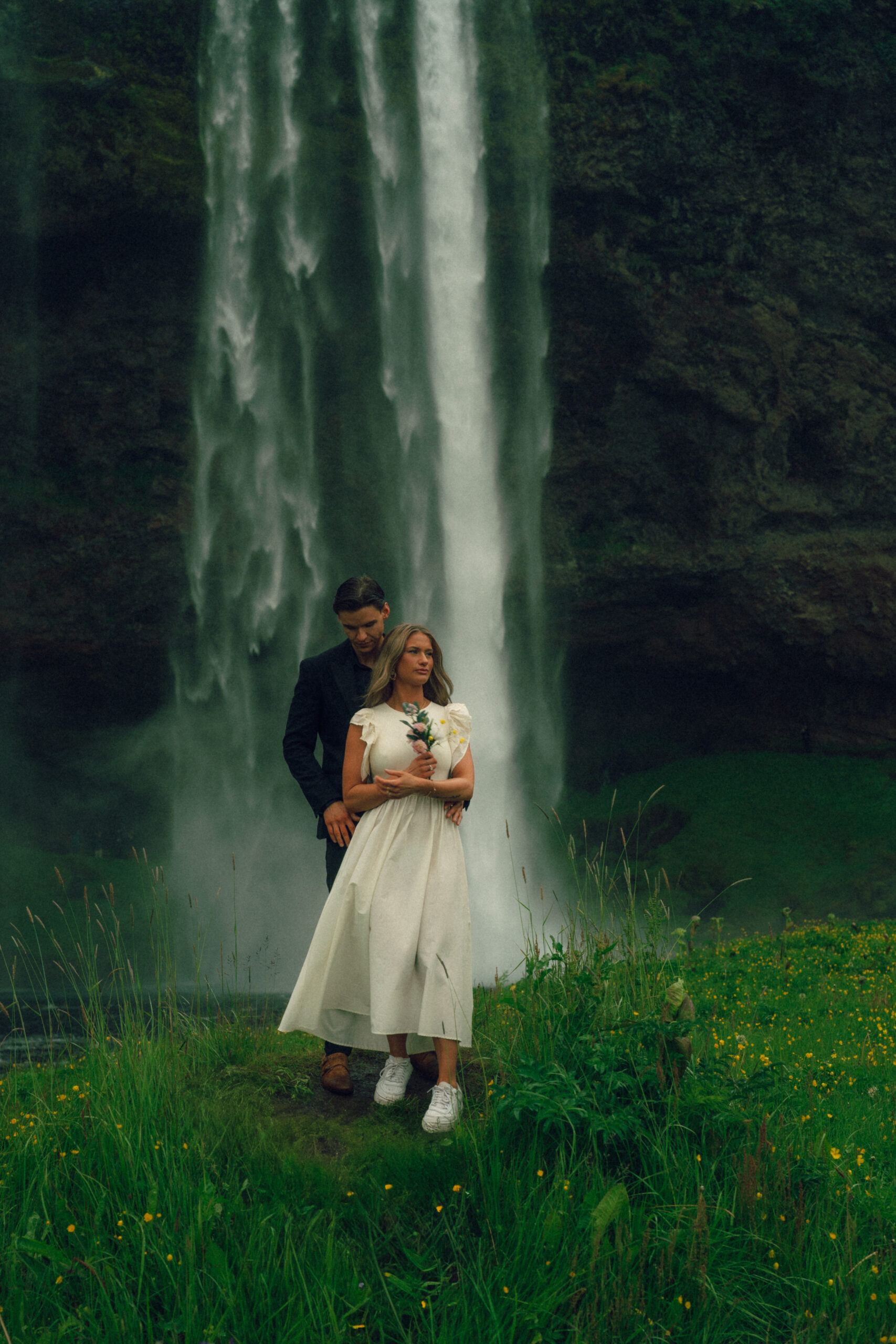 A cinematic photo of a couple in front of a waterfall during their elopement in Iceland.