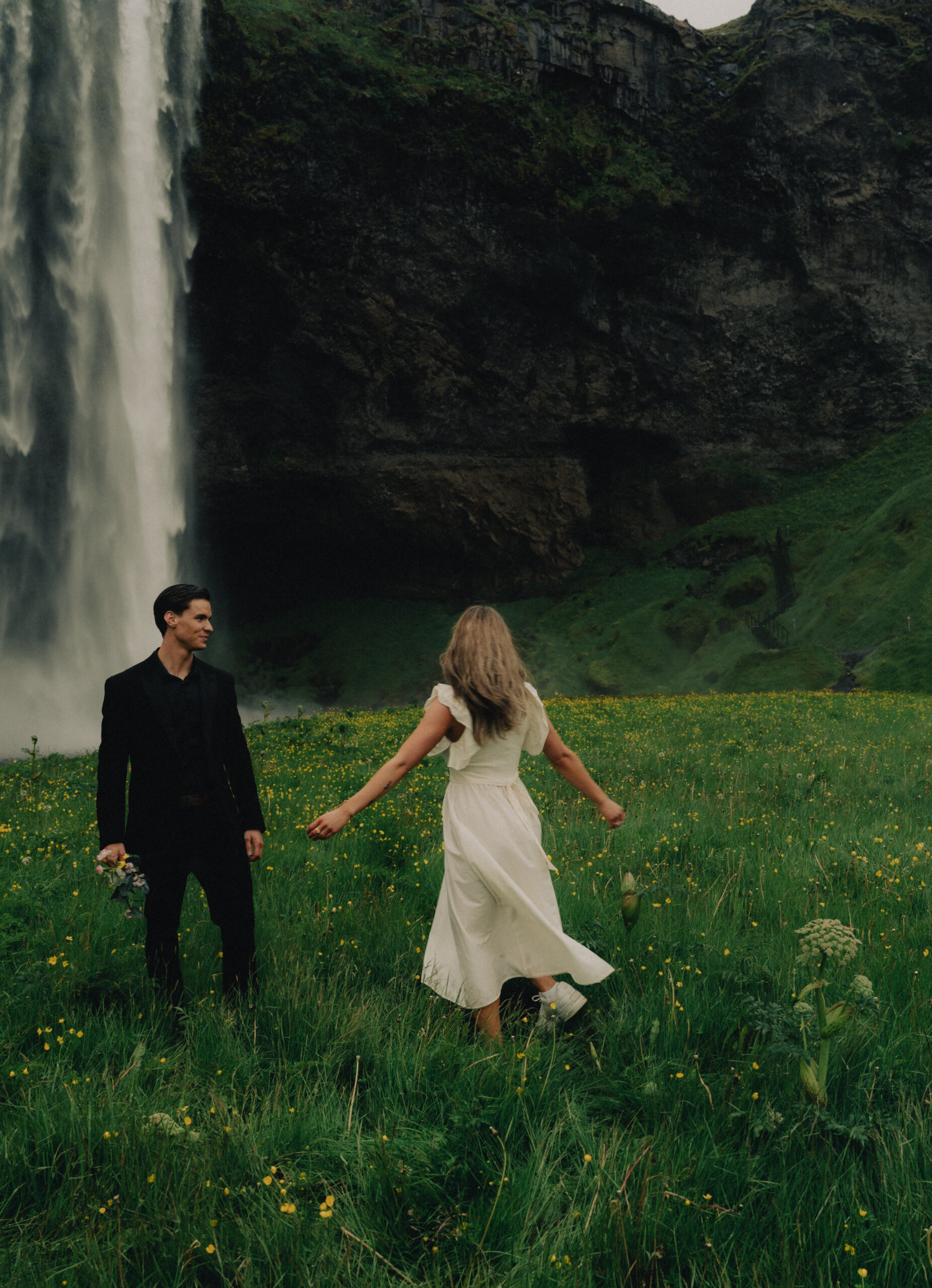 A cinematic photo of a couple in front of a waterfall during their elopement in Iceland.
