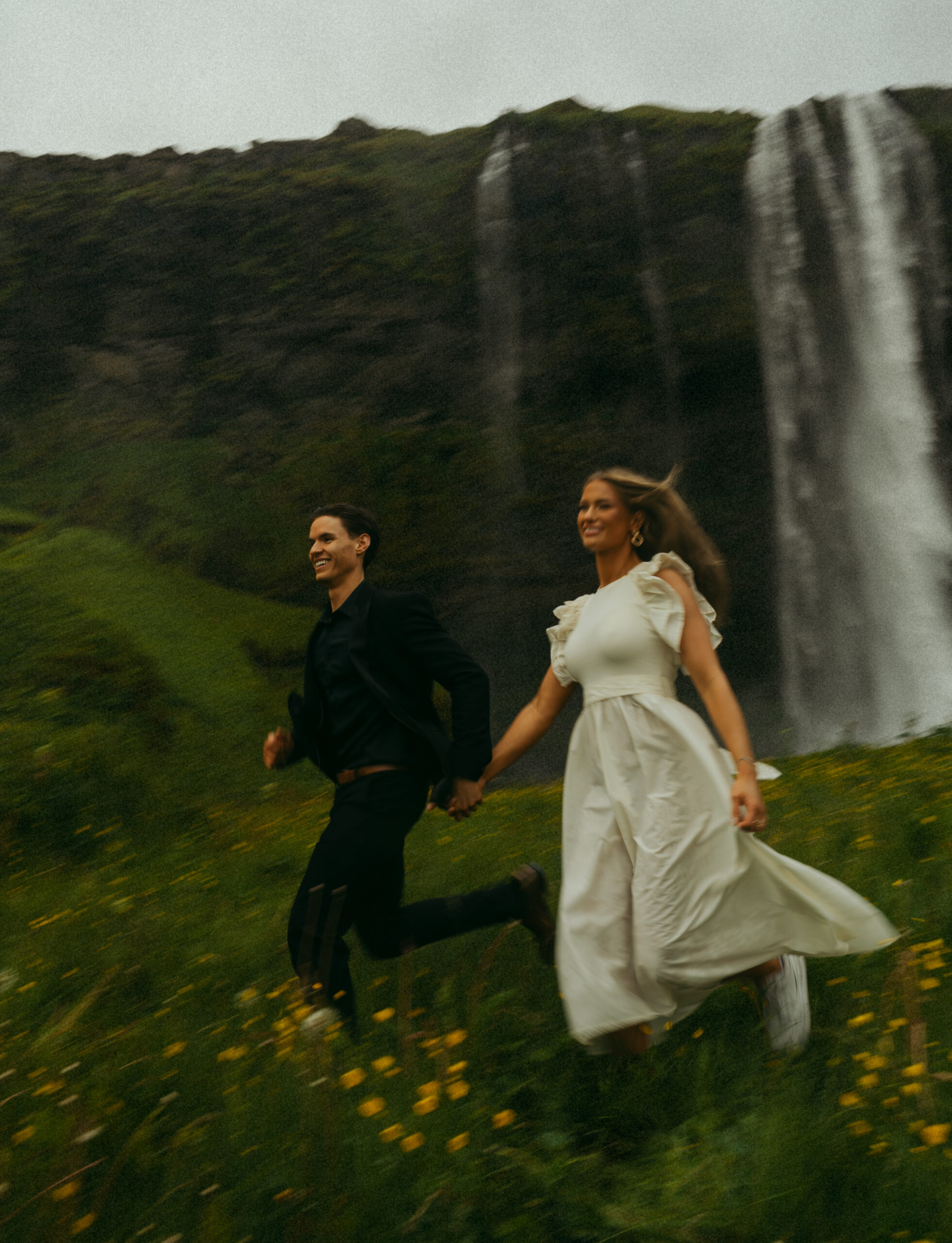 A cinematic photo of a couple in front of a waterfall during their elopement in Iceland.