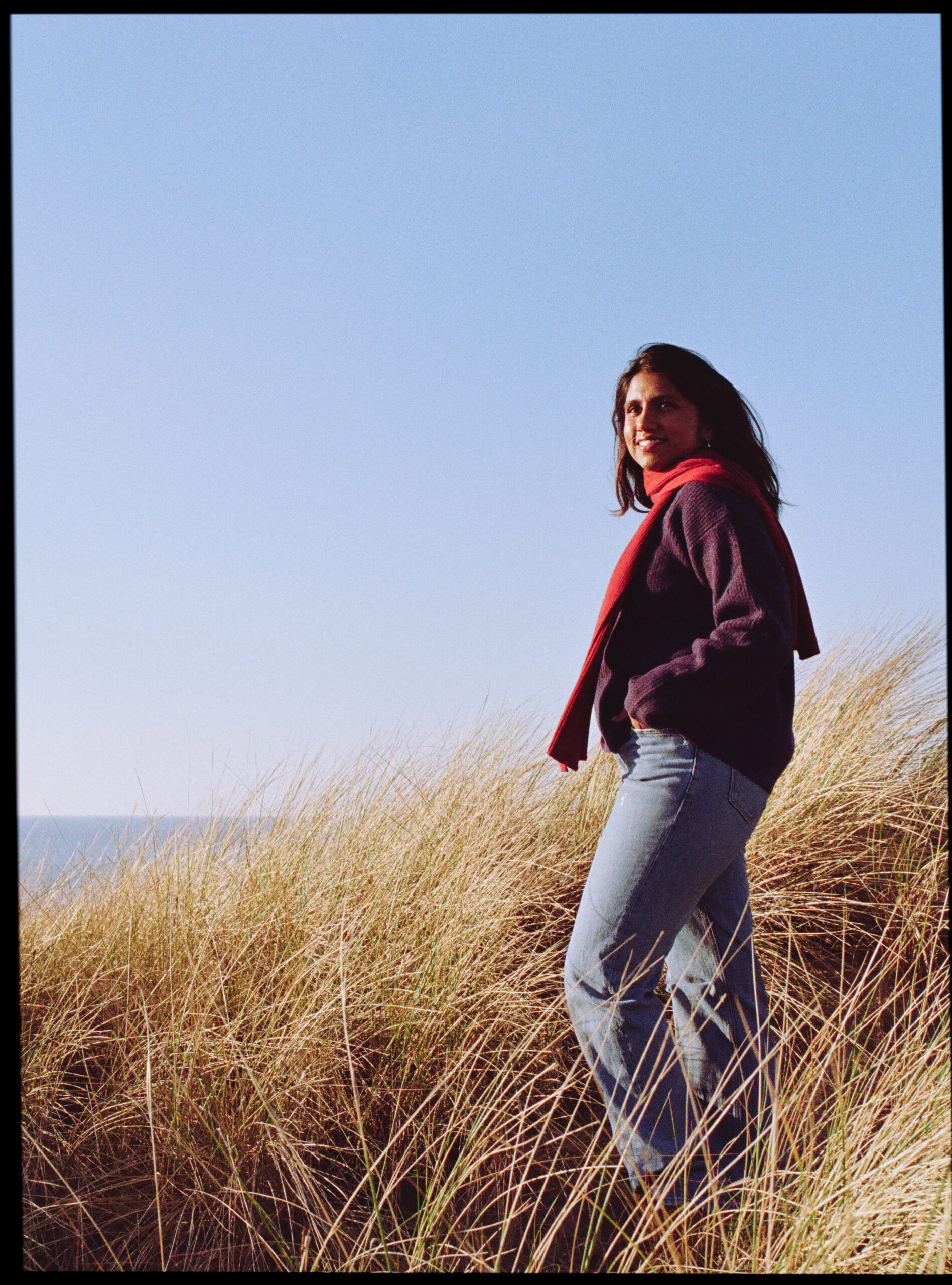 Kiki from Grainy Soul Photos posing in front of a beach in the Netherlands.