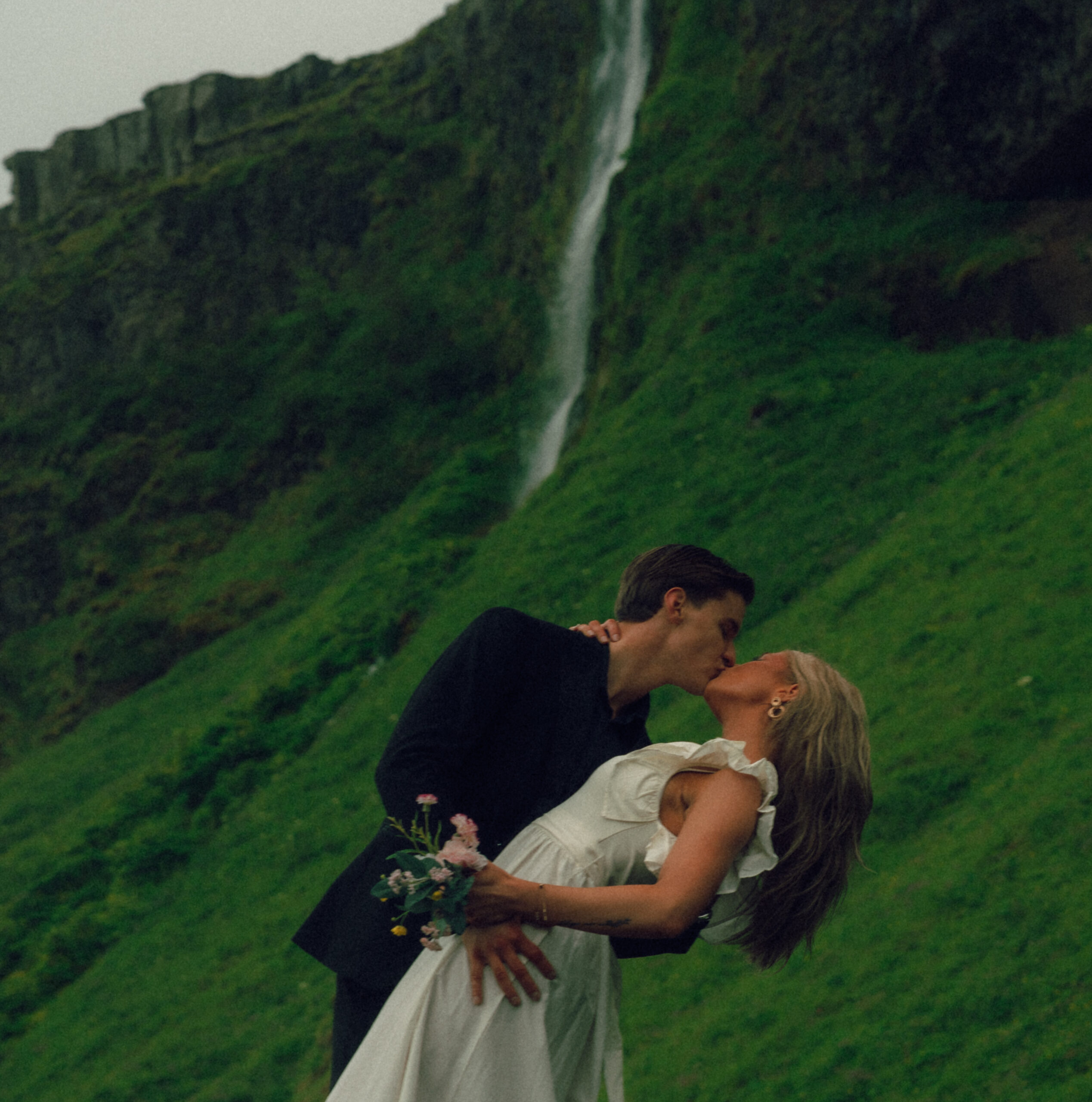 A cinematic photo of a couple in front of a waterfall during their elopement in Iceland.