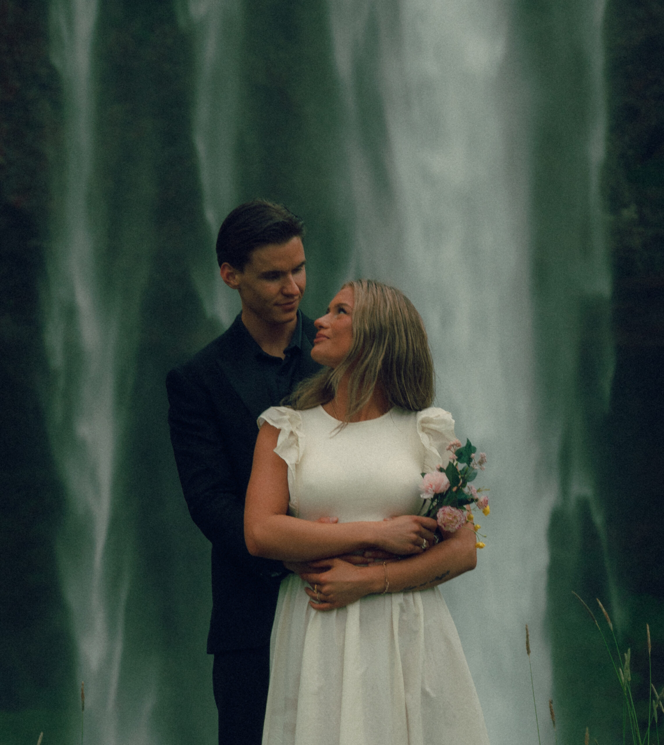 A cinematic photo of a couple in front of a waterfall during their elopement in Iceland.