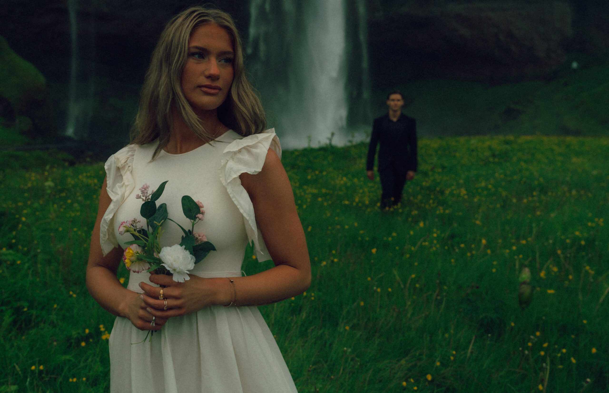 A cinematic photo of a couple in front of a waterfall during their elopement in Iceland.