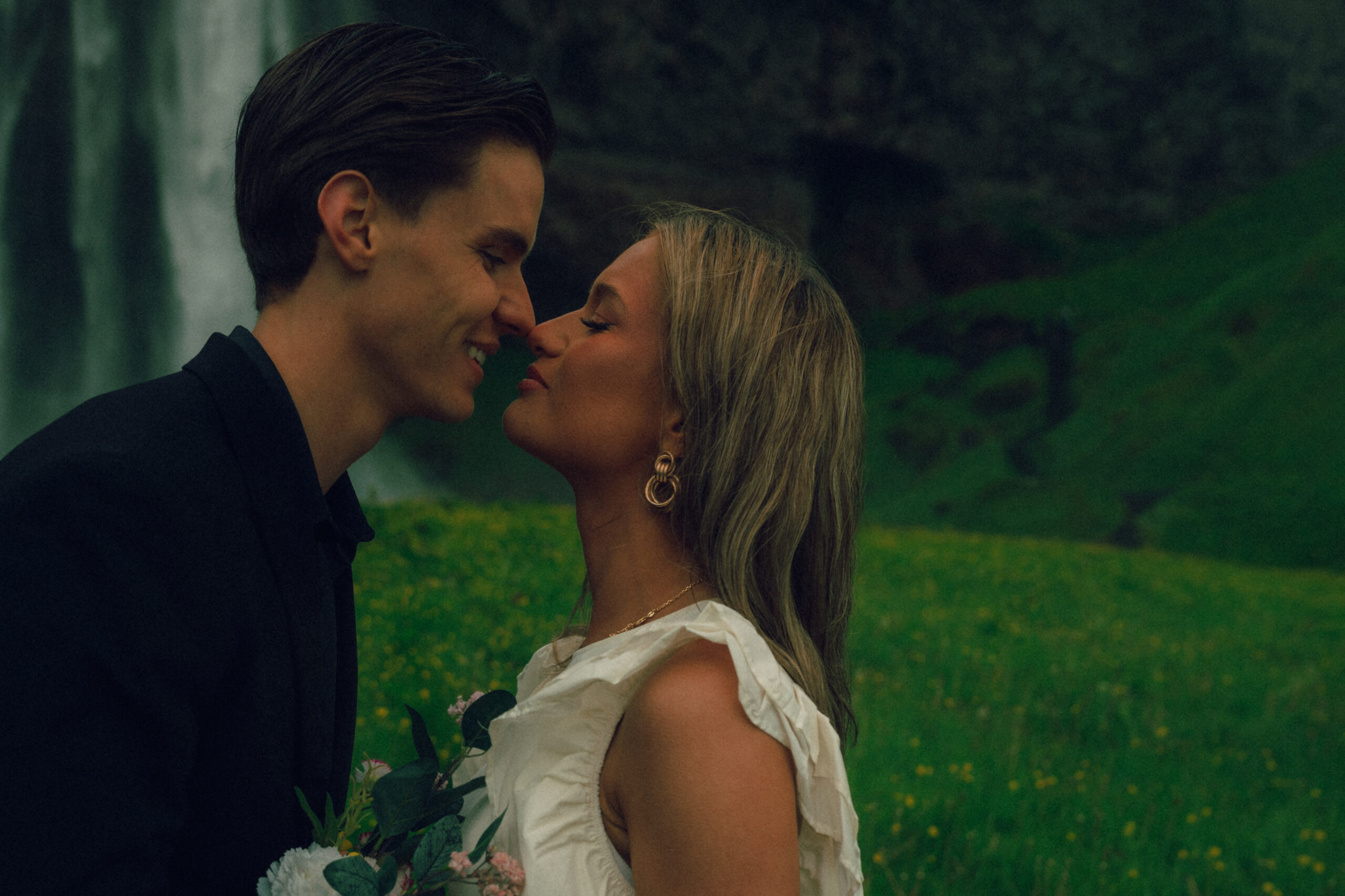 A cinematic photo of a couple in front of a waterfall during their elopement in Iceland.