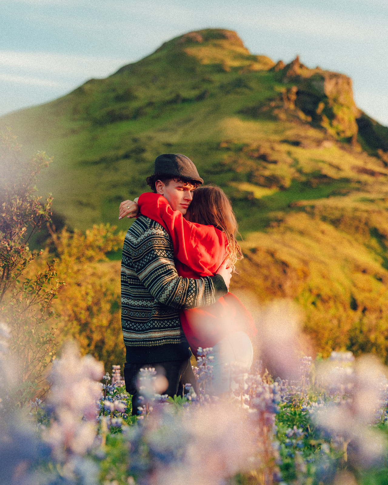 A cinematic photo of a couple in a meadow filled with lupins in Iceland.