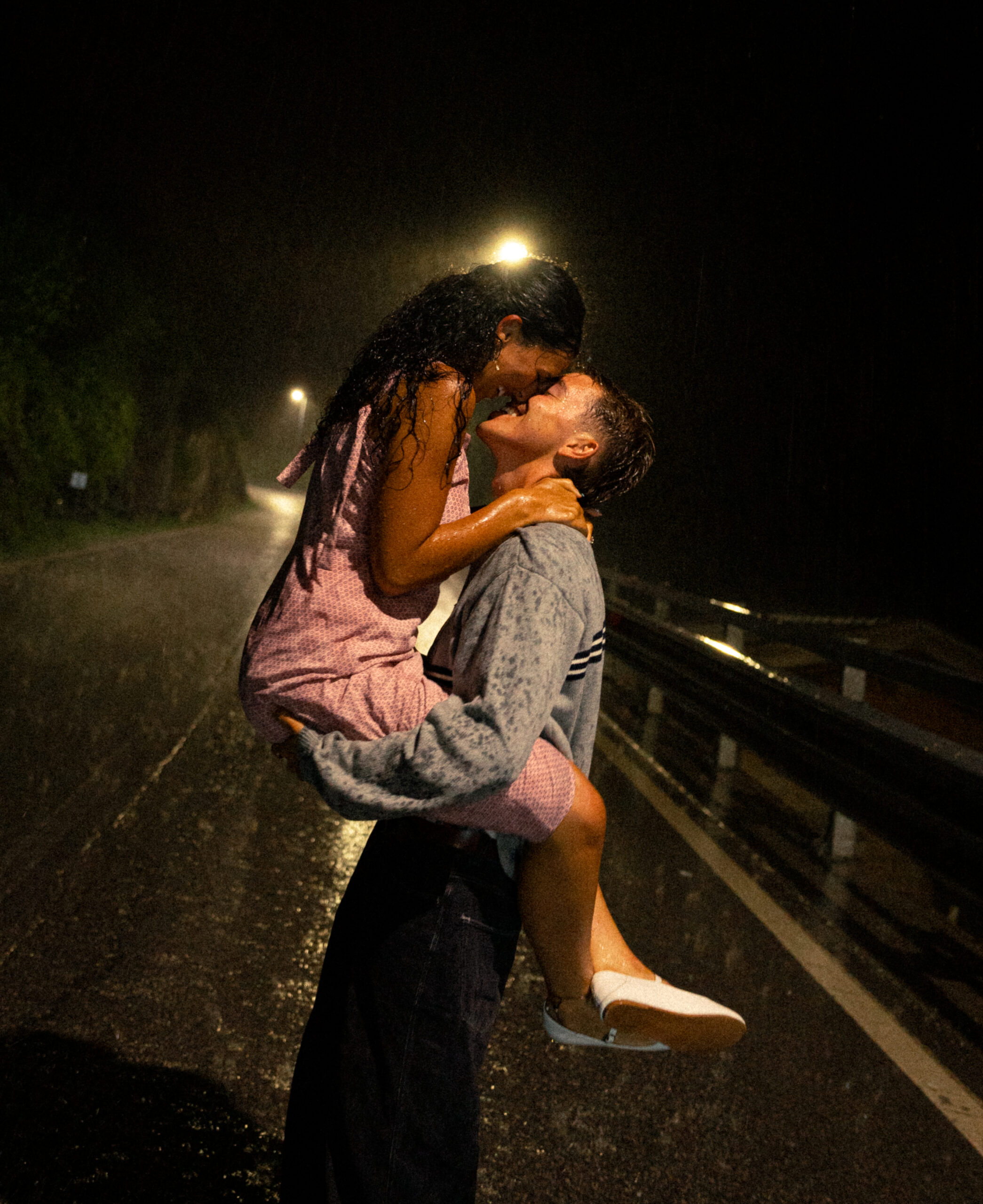 A cinematic photo of a couple posing in the streets of Italy at night during rain.