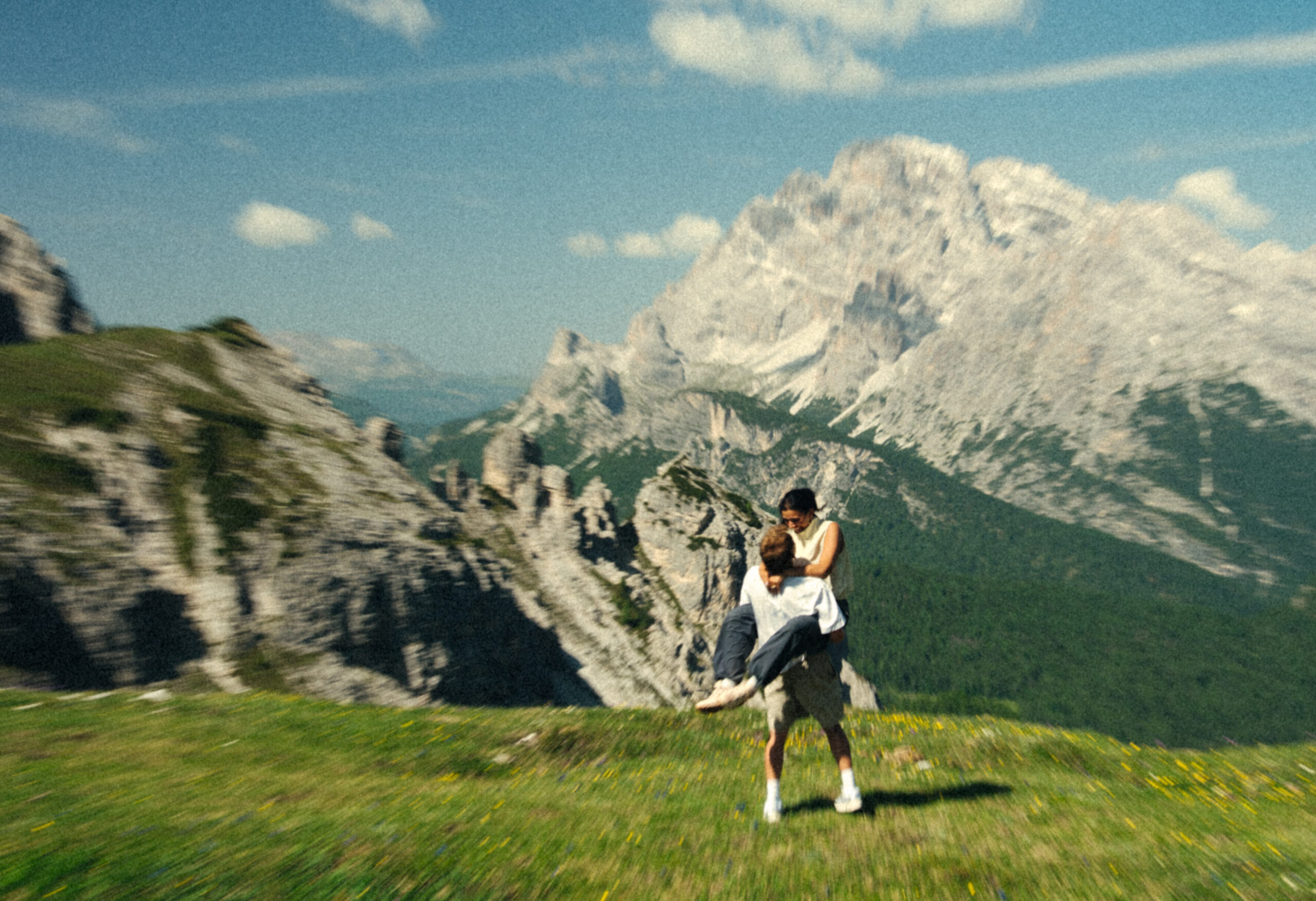 A cinematic photo of a couple posing with the Dolomites in the background.