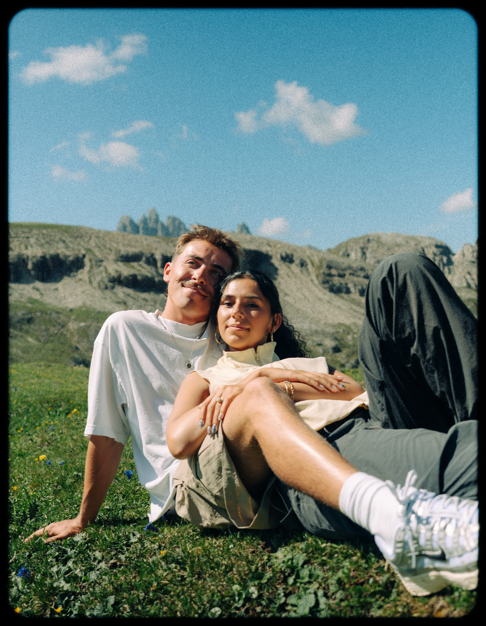 A cinematic photo of a couple posing with the Dolomites in the background.