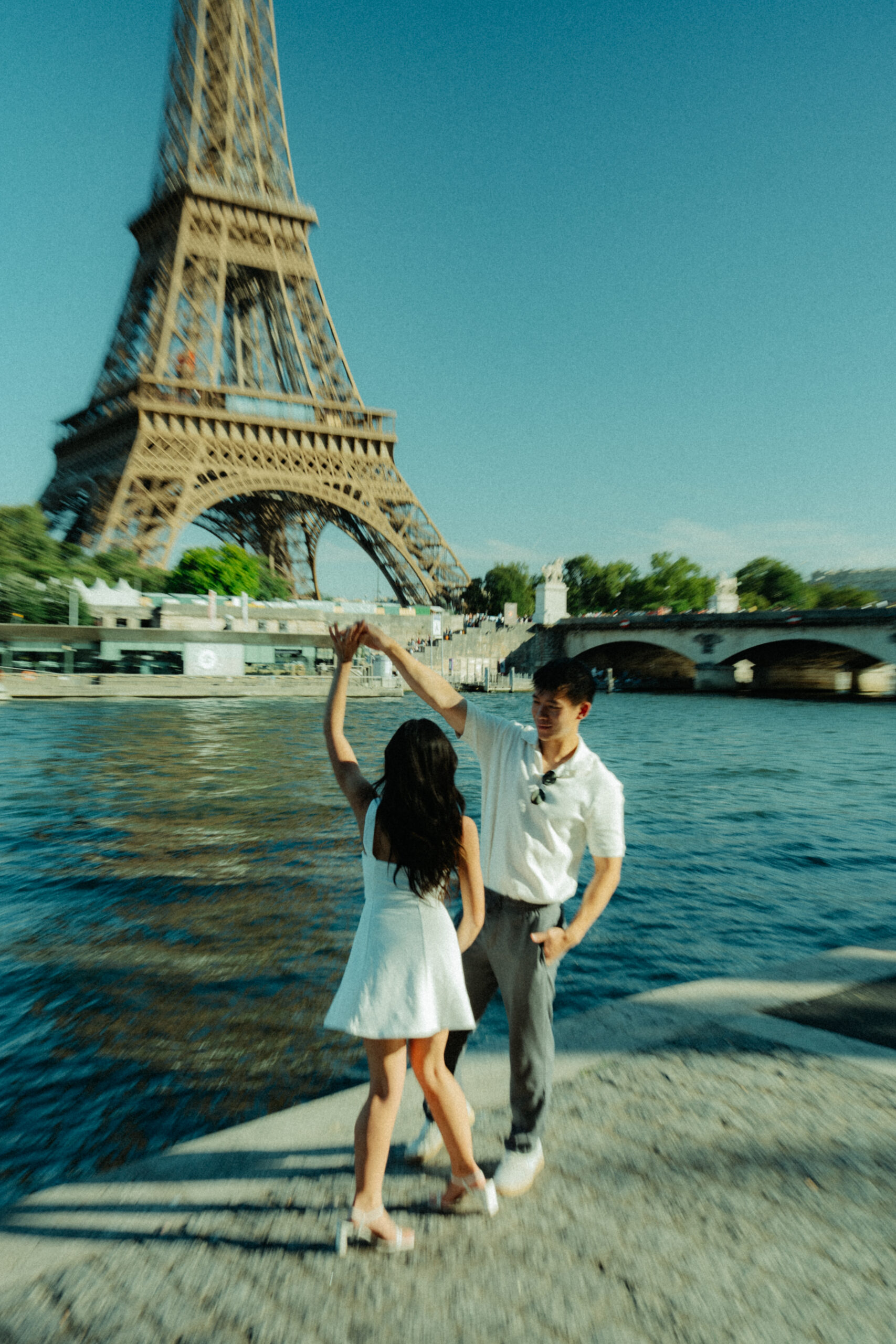 A cinematic photo of a couple posing in Paris with the Eiffel Tower in the background.