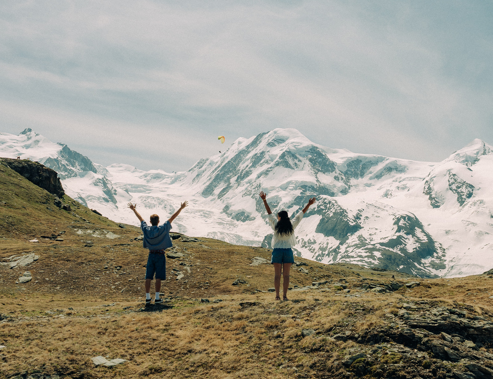 A cinematic photo of a couple posing in a meadow in Switzerland.