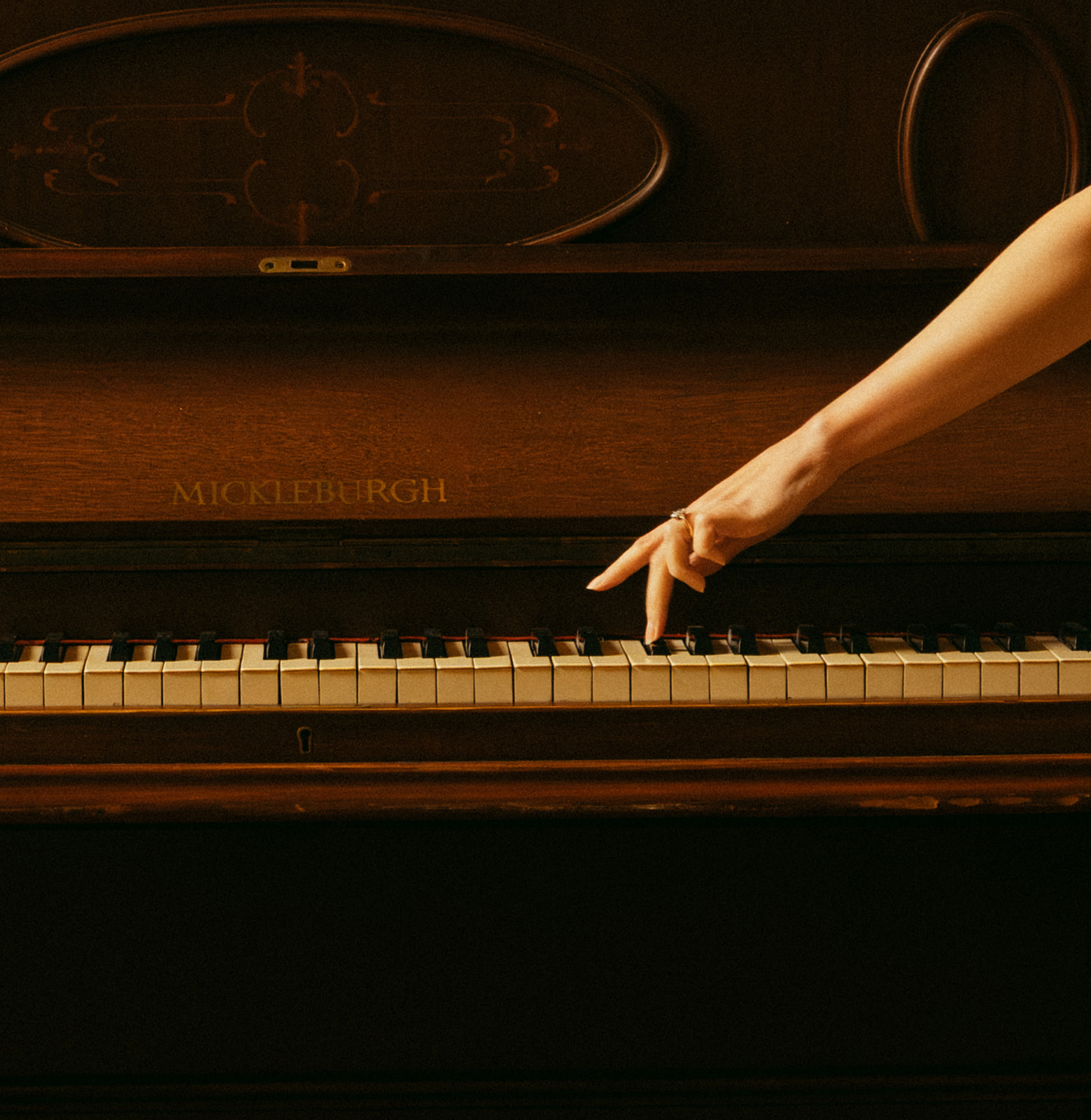 A detail shot of a bride's hand on a piano's keys during her elopement.