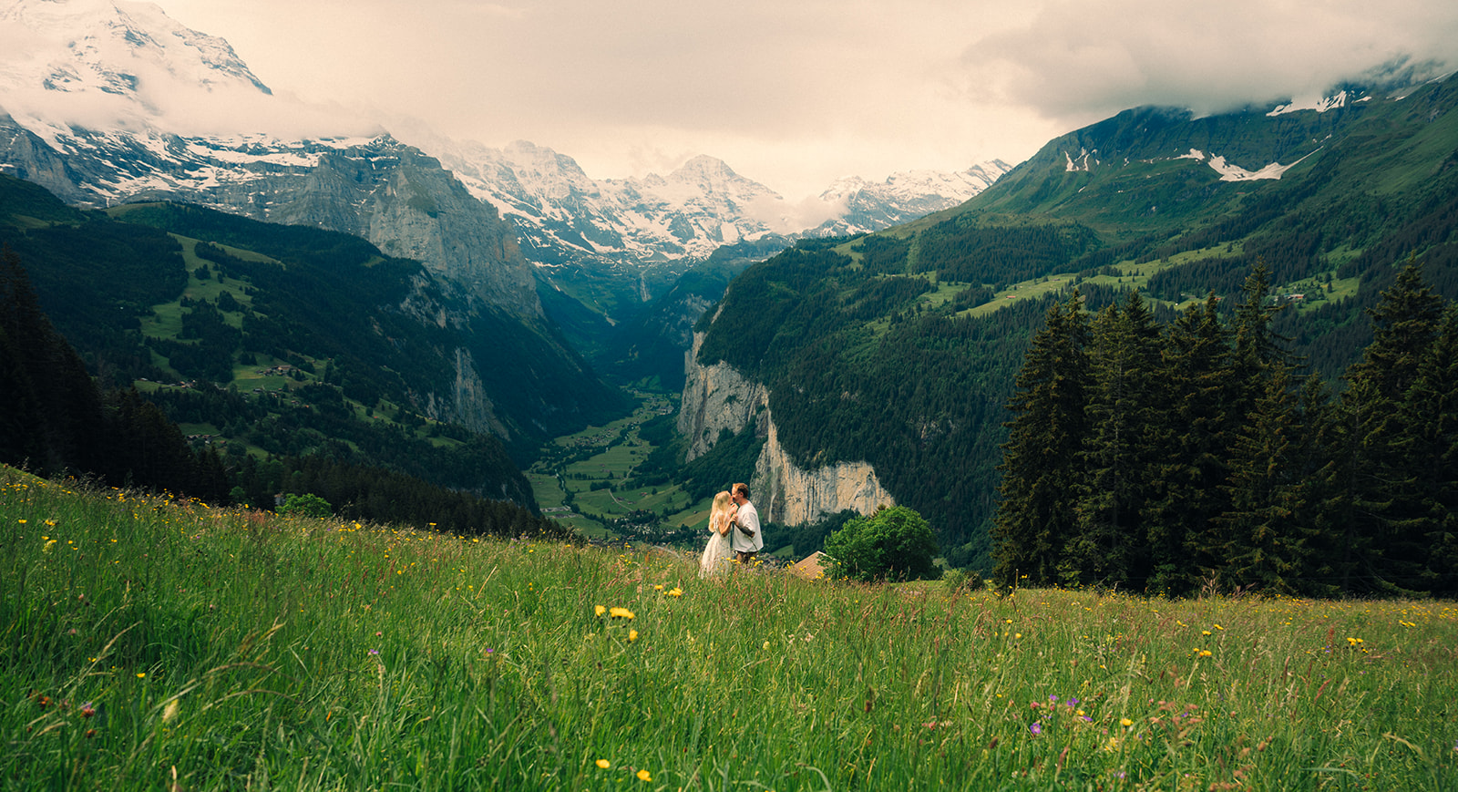 A cinematic photo of a couple posing near Wengen, Switzerland with the Swiss Alps in the background.