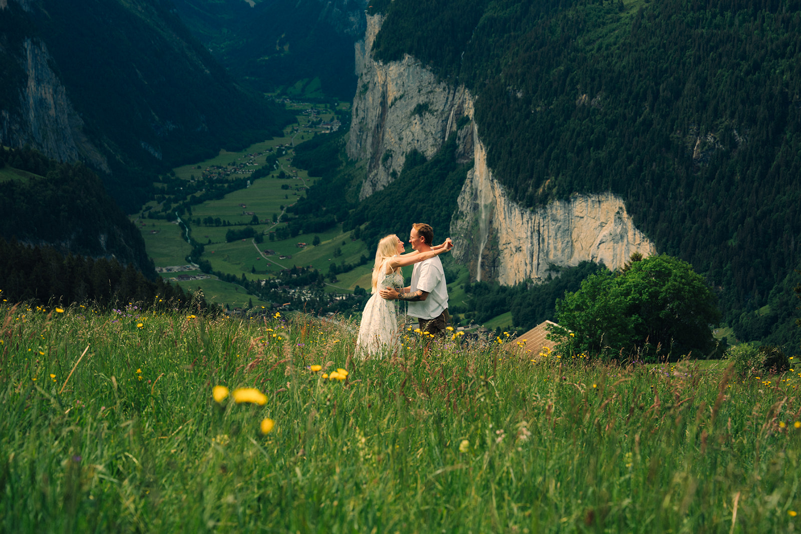 A cinematic photo of a couple posing near Wengen, Switzerland with the Swiss Alps in the background.