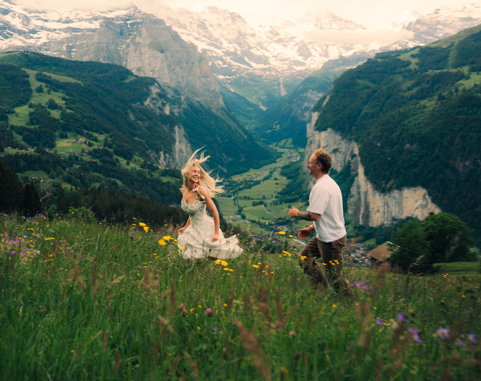 A cinematic photo of a couple posing near Wengen, Switzerland with the Swiss Alps in the background.