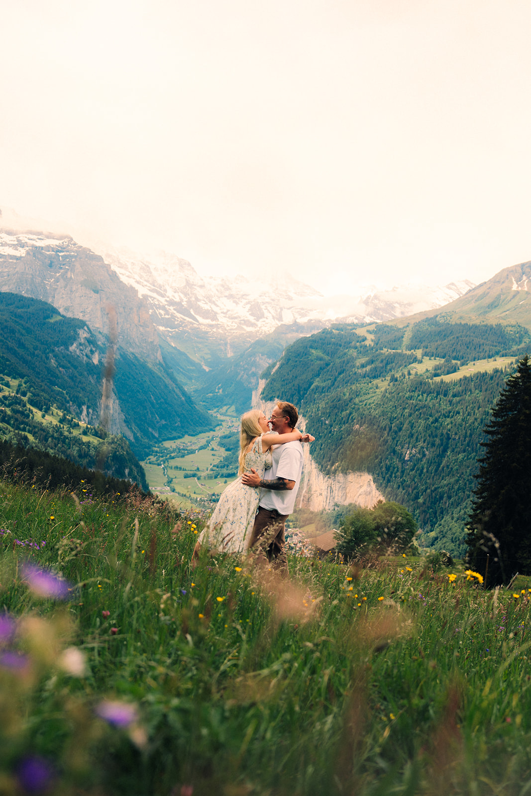A cinematic photo of a couple posing near Wengen, Switzerland with the Swiss Alps in the background.