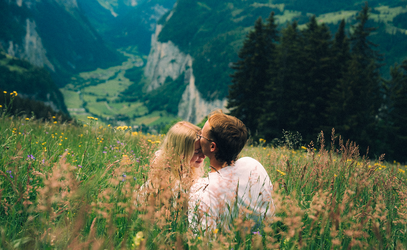 A cinematic photo of a couple posing near Wengen, Switzerland with the Swiss Alps in the background.