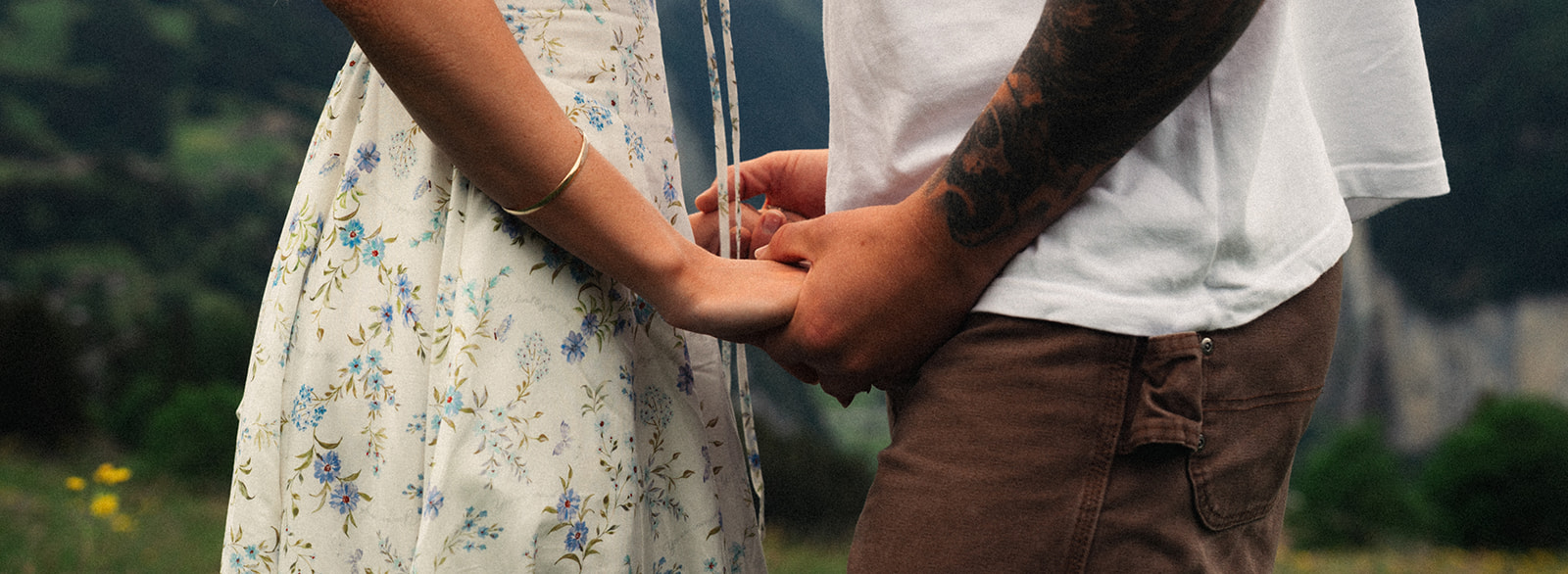 A cinematic detail shot of a couple's hands with the Swiss Alps in the background.