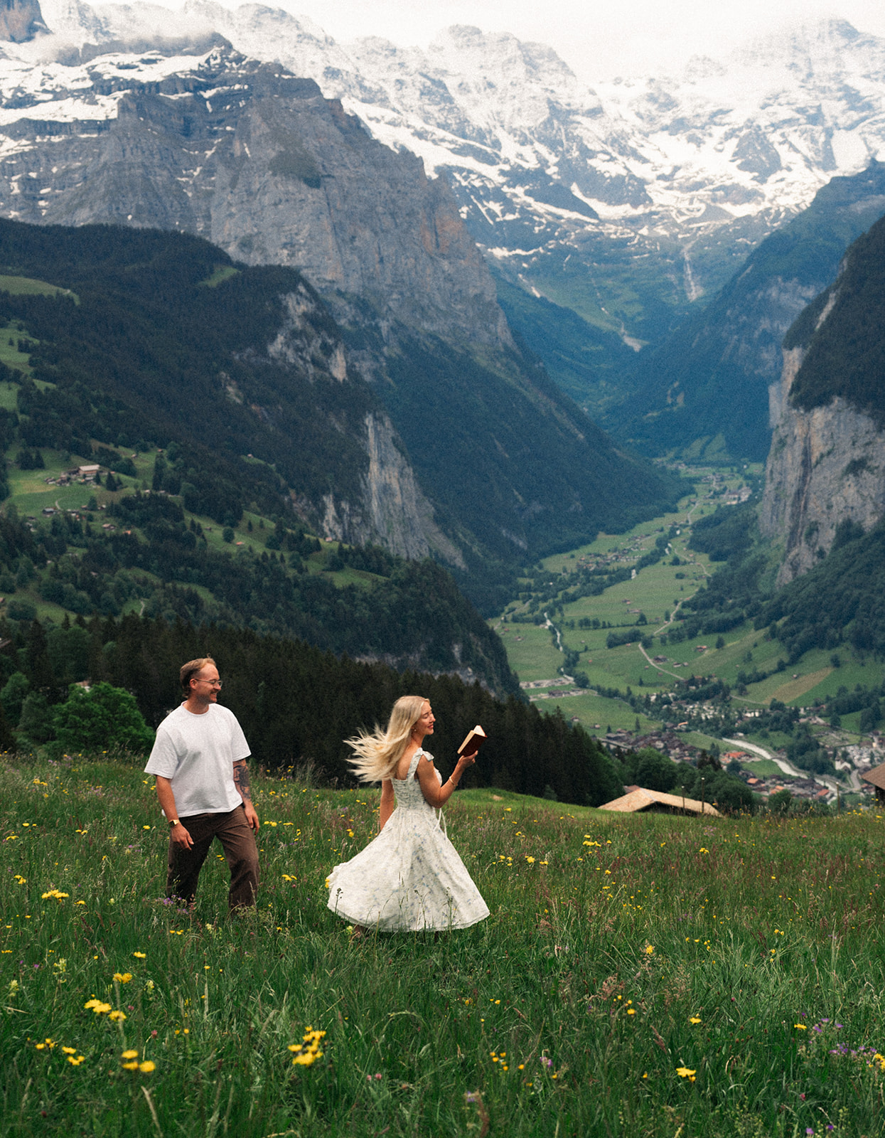 A cinematic photo of a couple posing near Wengen, Switzerland with the Swiss Alps in the background.