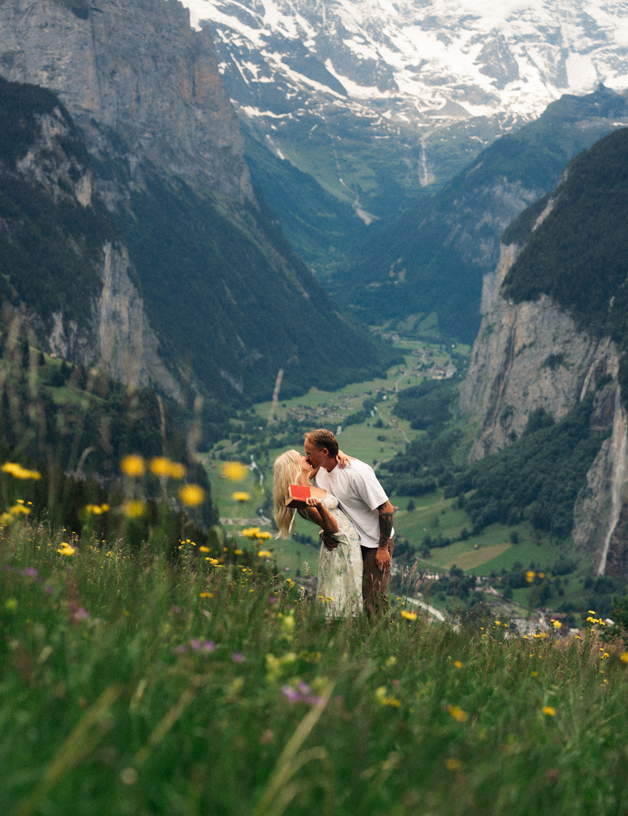 A cinematic photo of a couple posing near Wengen, Switzerland with the Swiss Alps in the background.