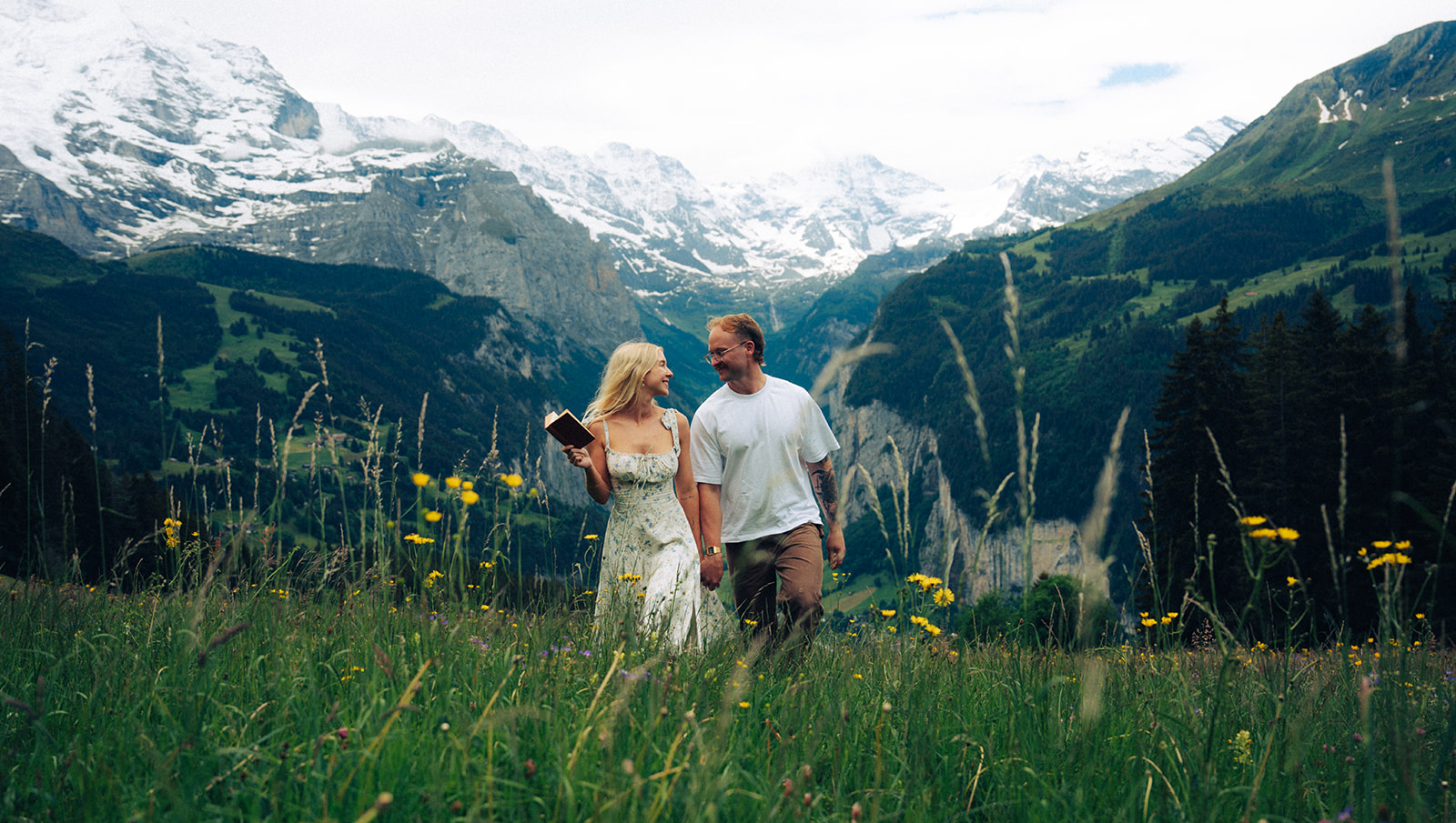 A cinematic photo of a couple posing near Wengen, Switzerland with the Swiss Alps in the background.
