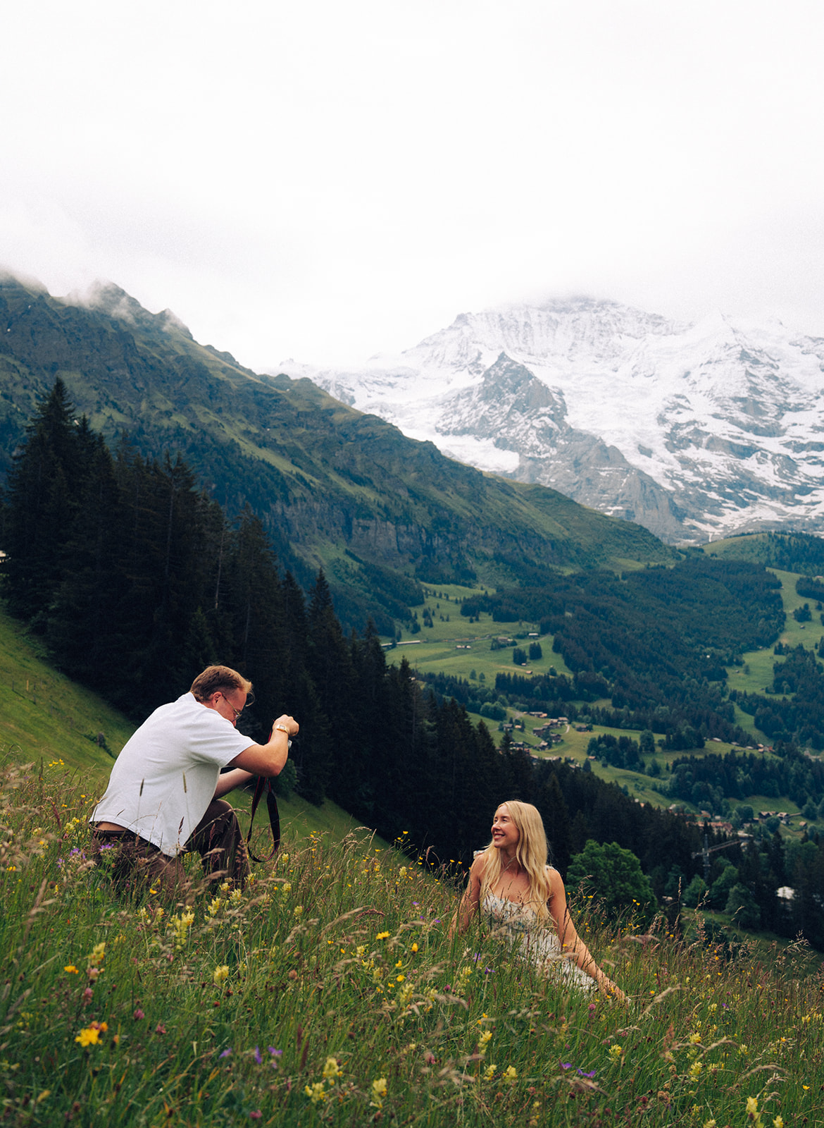 A cinematic photo of a couple posing near Wengen, Switzerland with the Swiss Alps in the background.
