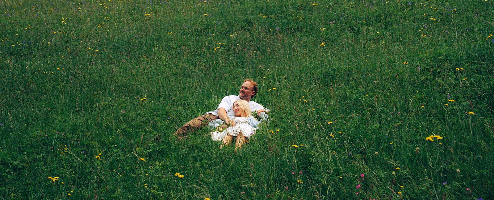 A cinematic photo of a couple posing in a meadow near Wengen, Switzerland.