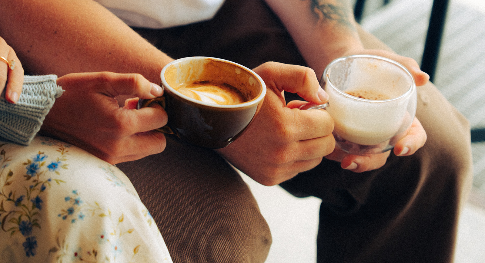 A cinematic detail shot of a couple's hands with coffee cups in a cafe in Wengen, Switzerland.