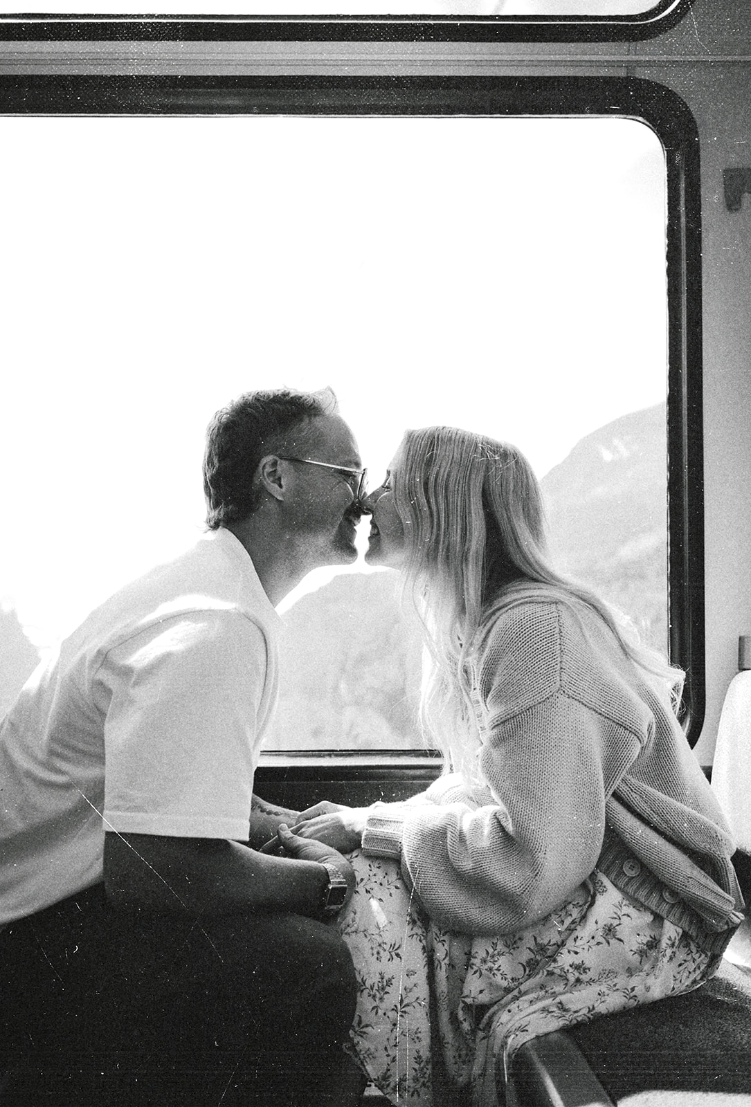A cinematic photo of a couple in a train with the Swiss alps in the background.