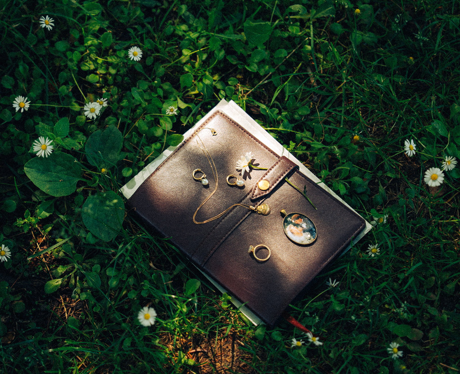 A wedding flat lay of vow book, heirlooms, and rings on a meadow in Switzerland.