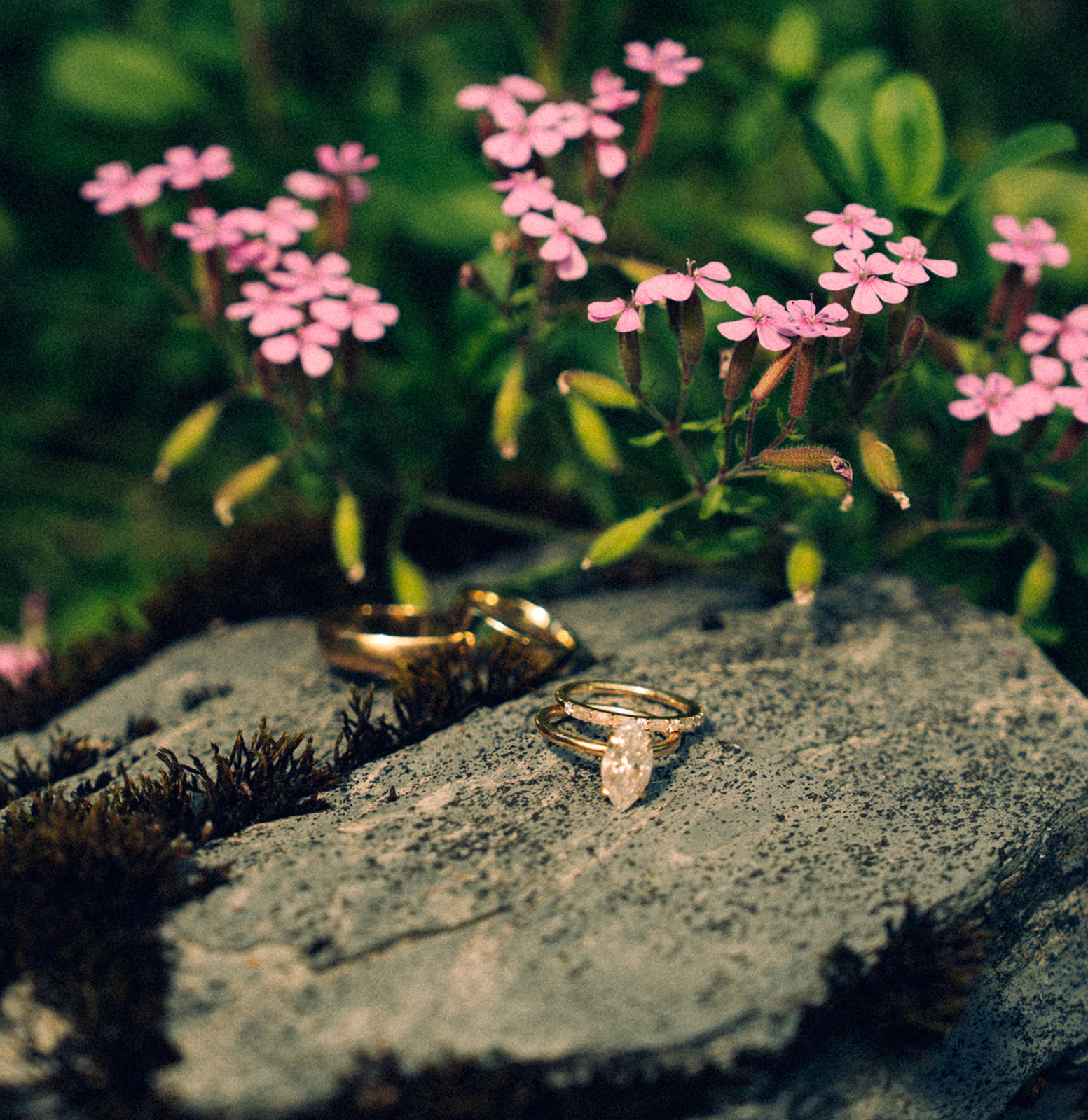 A wedding flat lay of rings on a rock surrounded by flowers in Switzerland.