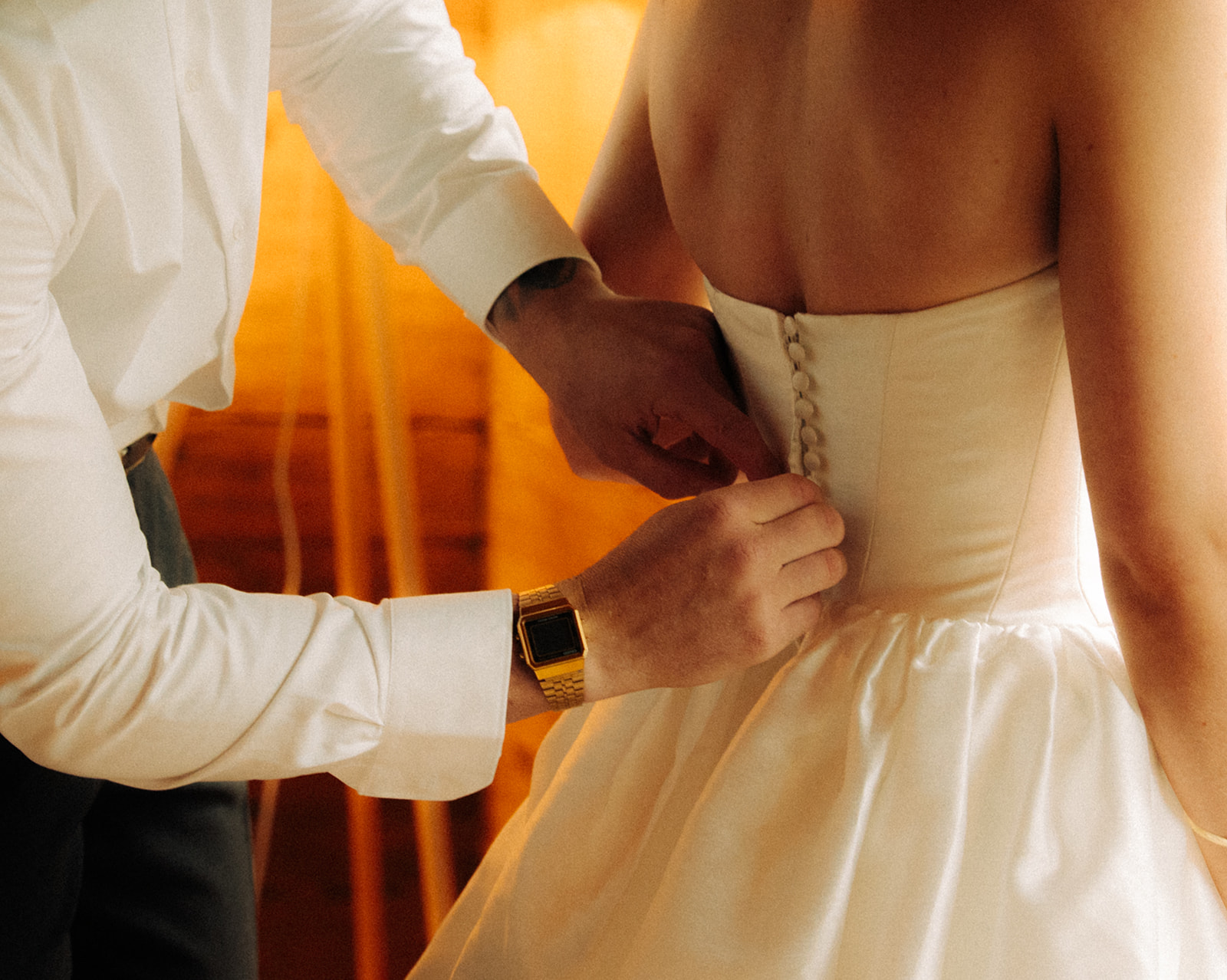 A cinematic photo of a bridegroom helping the bride get ready in their cabin in Innertkirchen, Switzerland for their elopement.