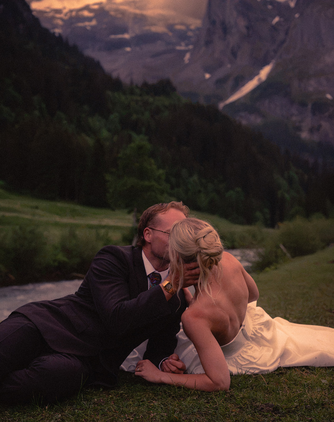 A cinematic photo of a bride and bridegroom kissing during their elopement in Rosenlaui, Switzerland with the Swiss alps in the background.