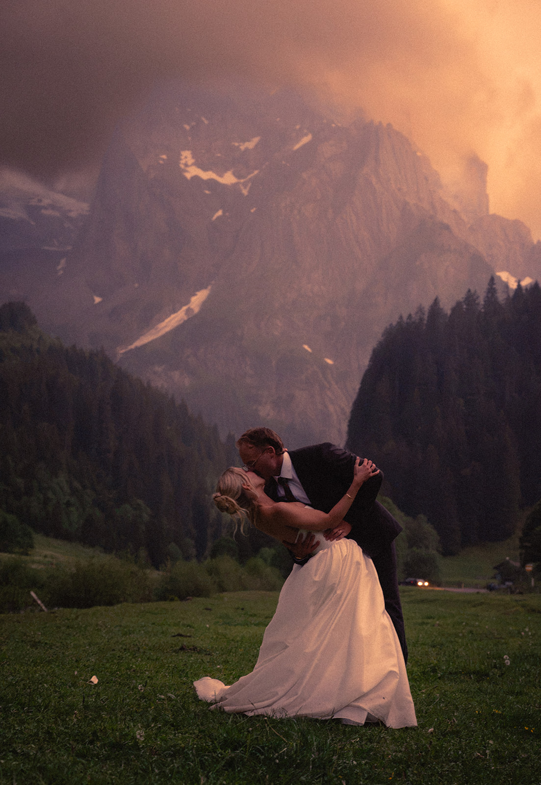 A cinematic photo of a bride and bridegroom dancing during their elopement in Rosenlaui, Switzerland with the Swiss alps in the background.